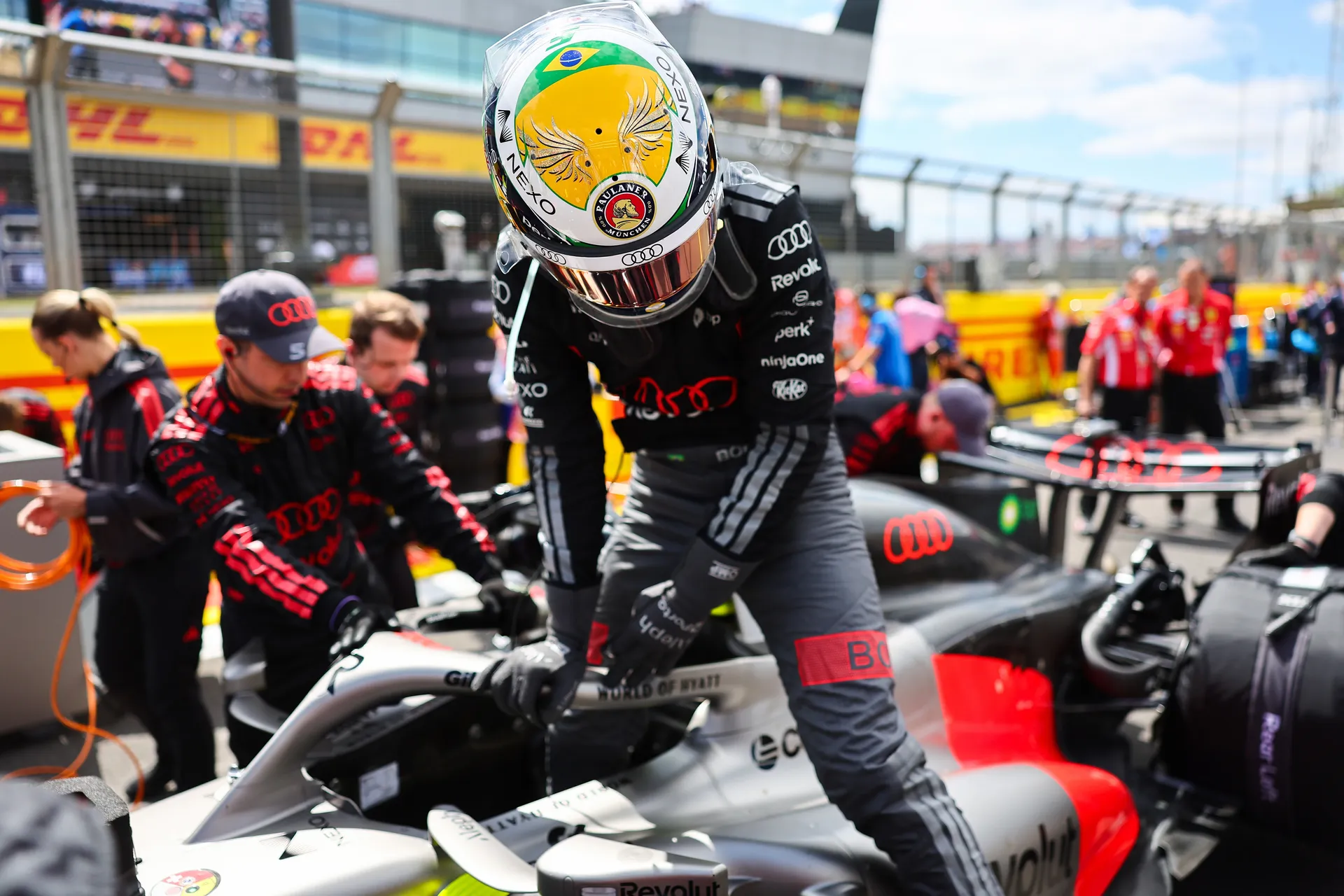 Gabriel Bortoleto stepping out of the Audi Revolut F1® Team car on the grid as mechanics prepare the car around him before the session.