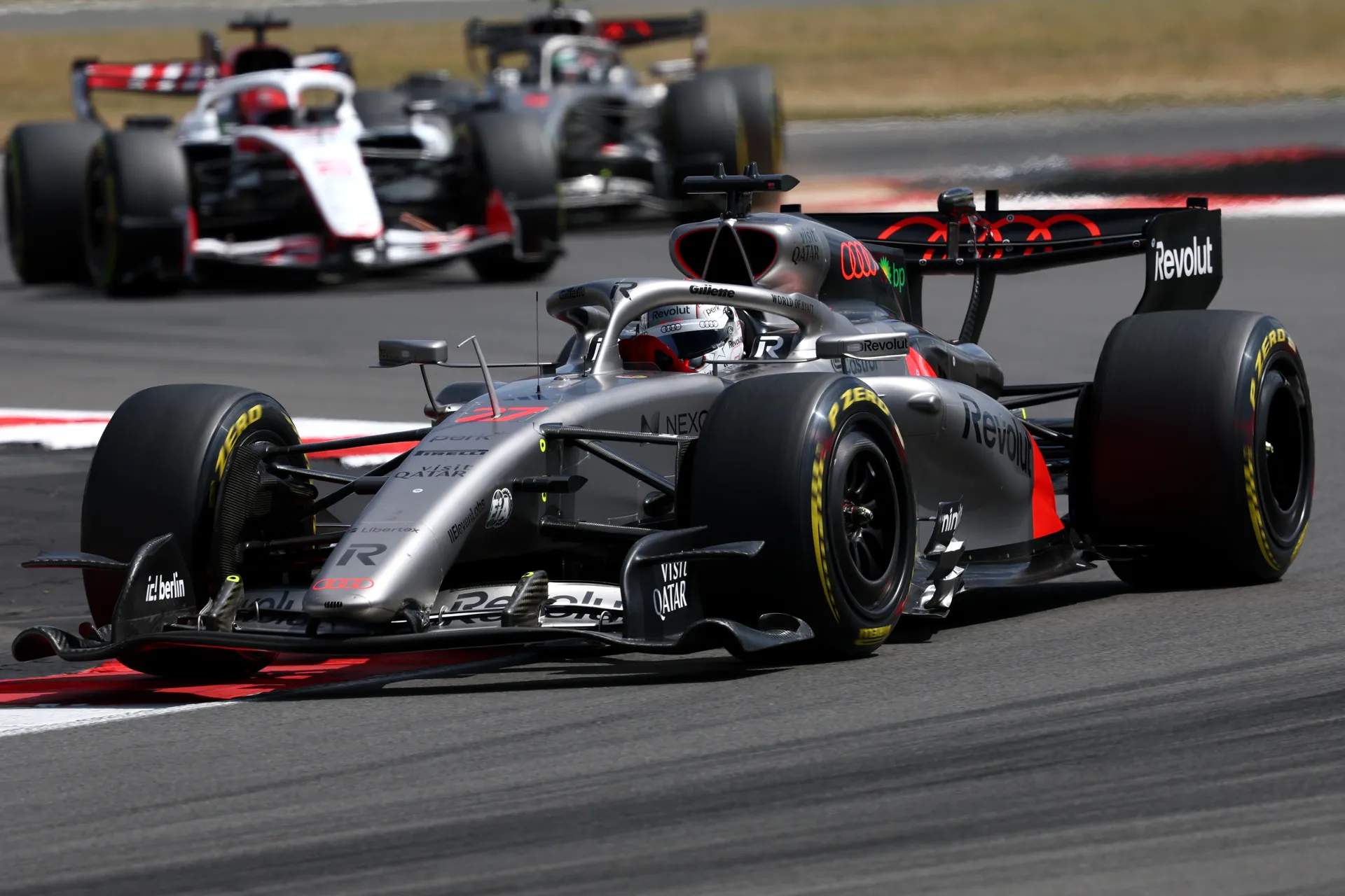 Audi Revolut F1® Team car driven by Nico Hulkenberg racing through a corner with another car following closely behind.