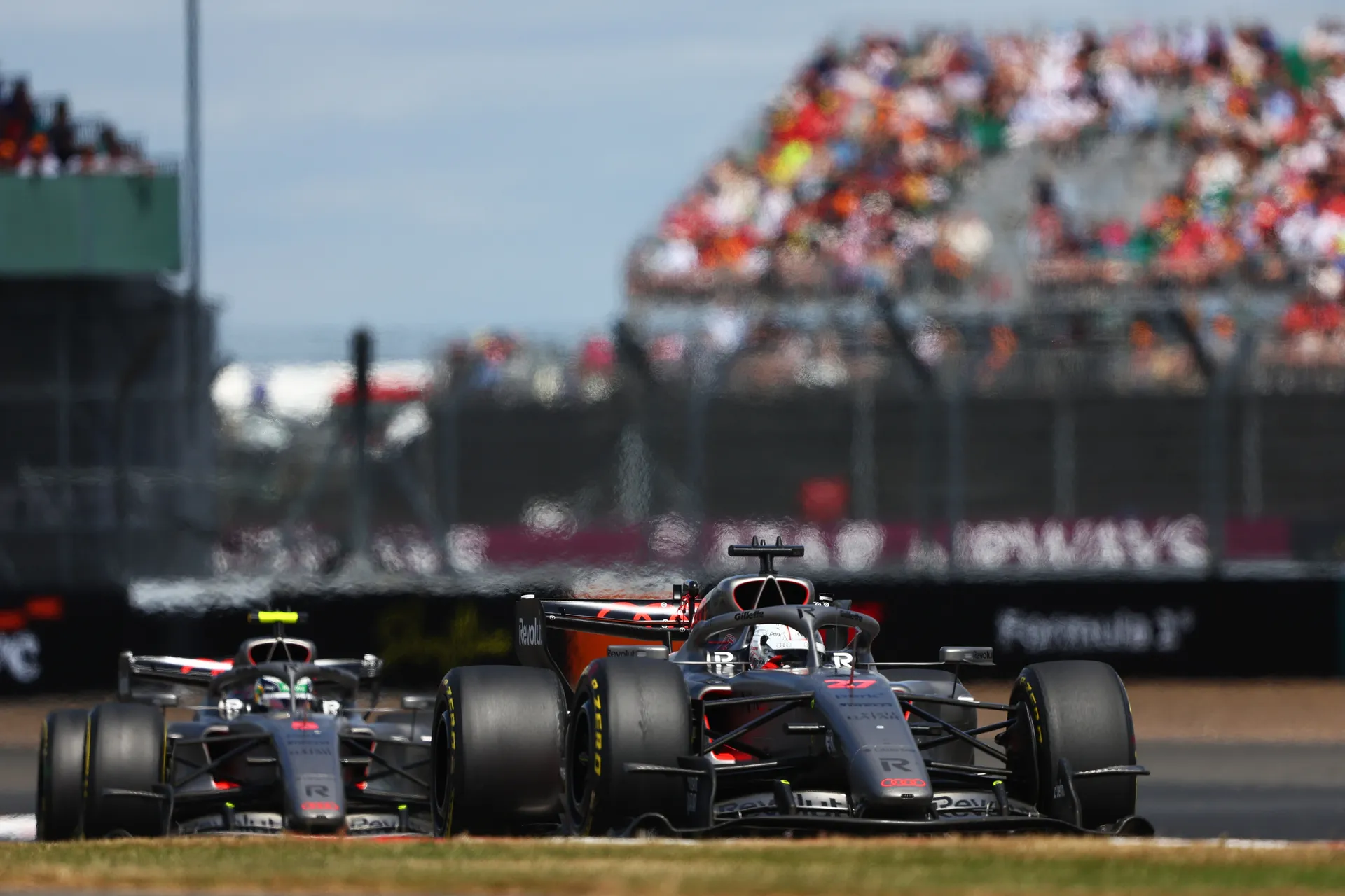 Two Audi Revolut F1® Team cars racing in formation, Nico Hulkenberg leading ahead of teammate Gabriel Bortoleto.