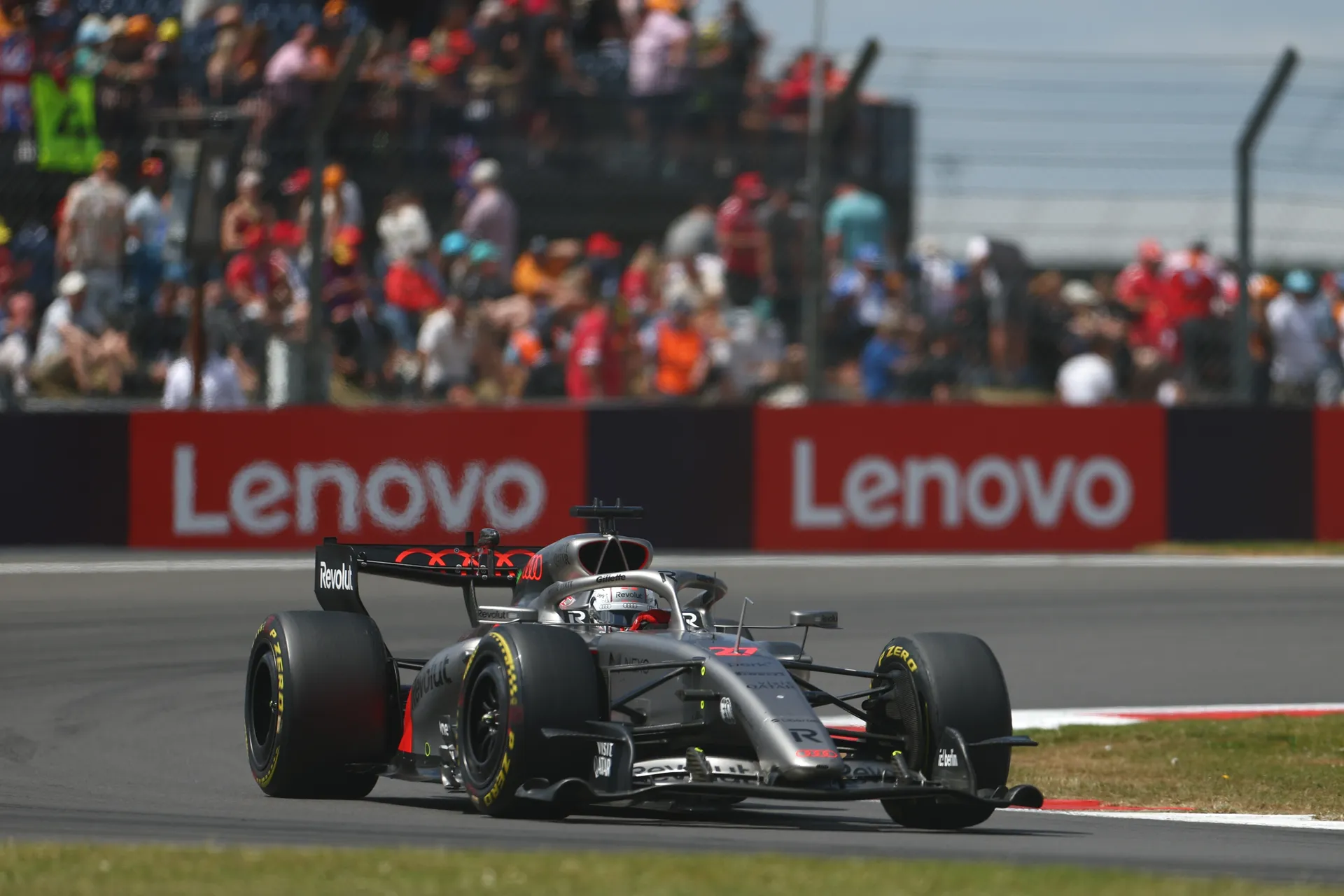 Audi Revolut F1® Team car driven by Nico Hulkenberg navigating a corner with crowd and trackside branding in the background.