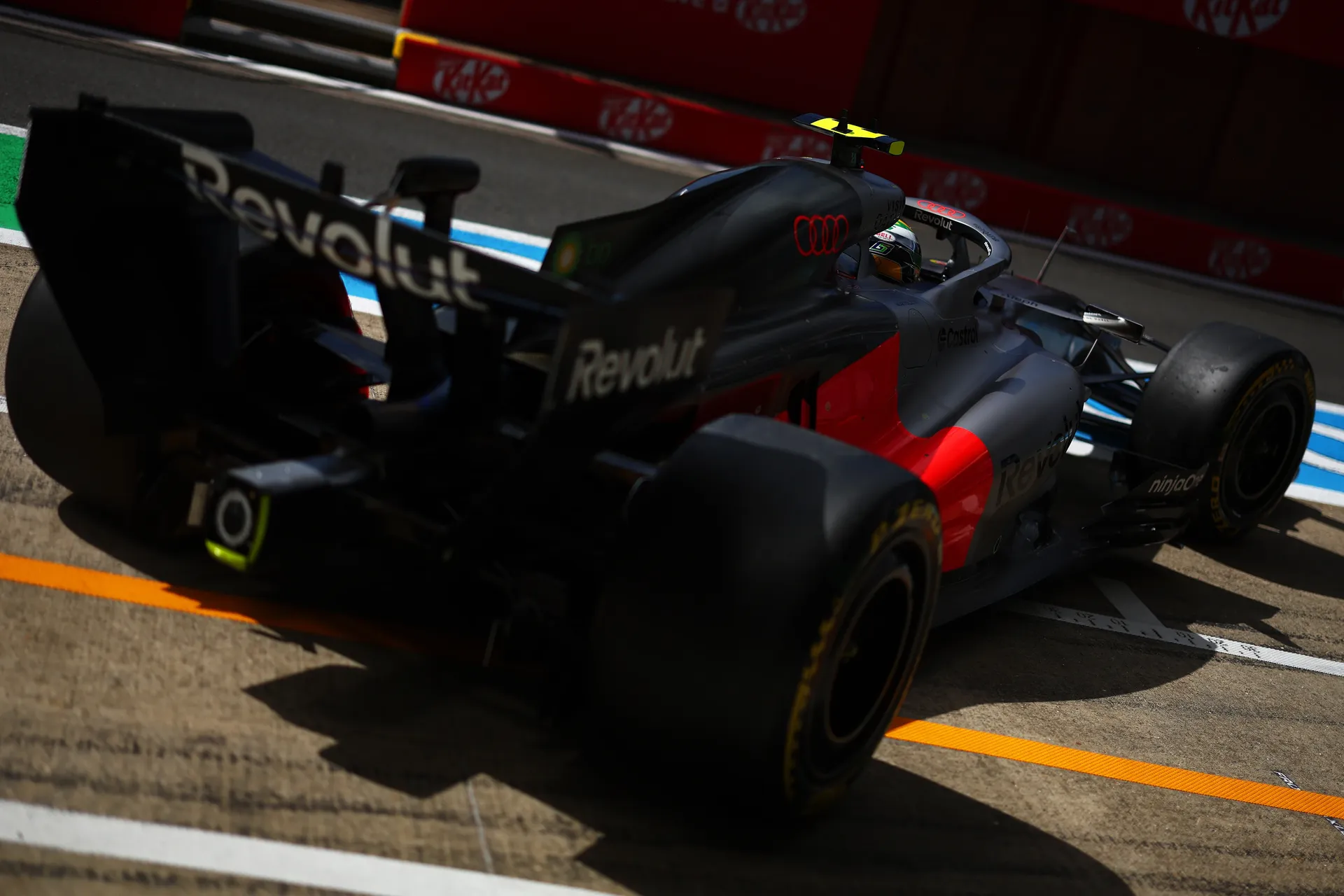 Rear three-quarter view of Audi Revolut F1® Team car driven by Gabriel Bortoleto exiting the pit lane under sunlight.