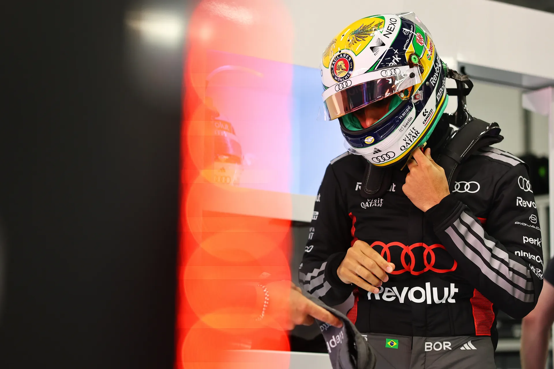 Gabriel Bortoleto adjusts his helmet and race suit inside the Audi Revolut F1® Team garage before heading out.