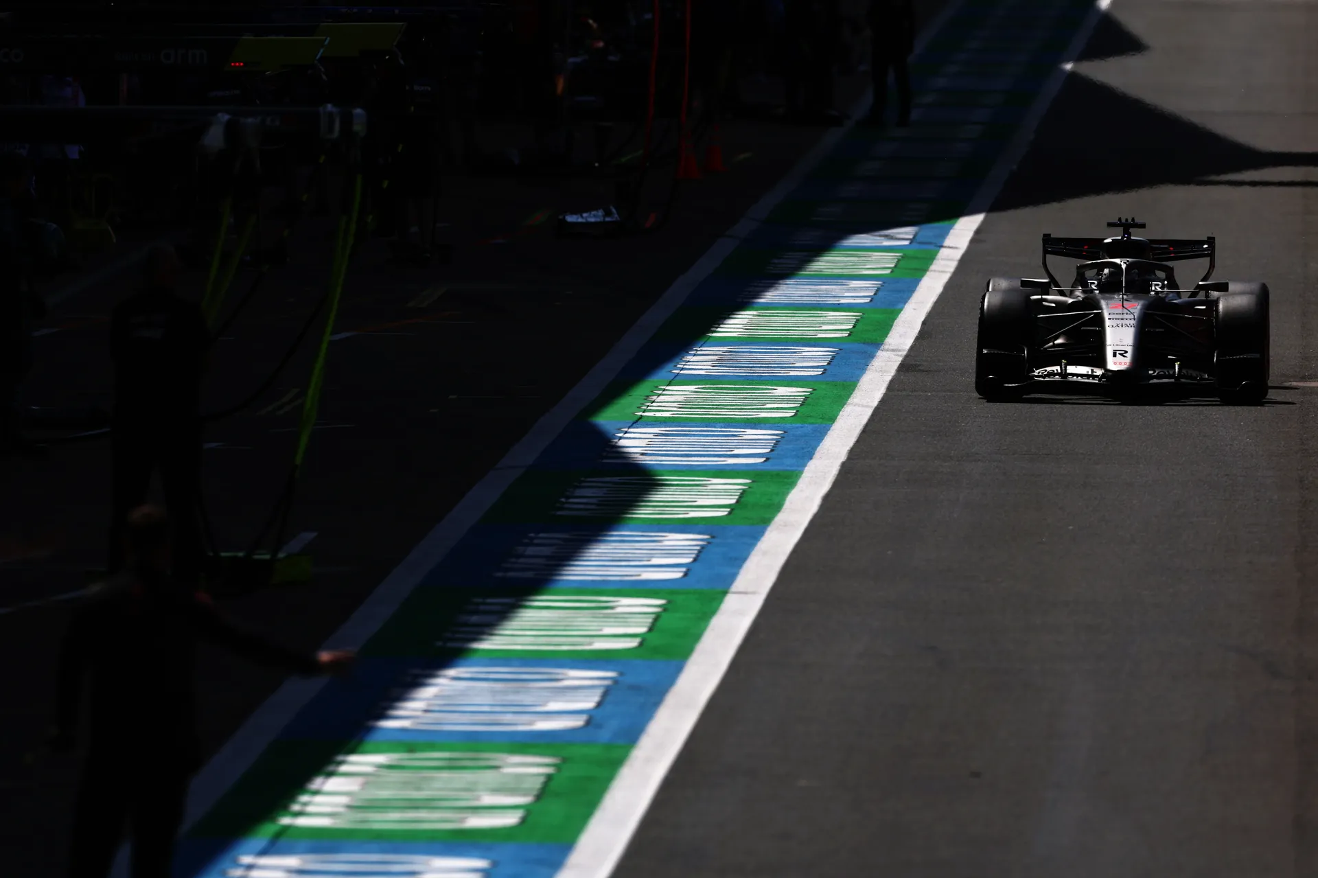 The Audi R26 drives down the pit lane in strong light and shadow during a session at Silverstone.