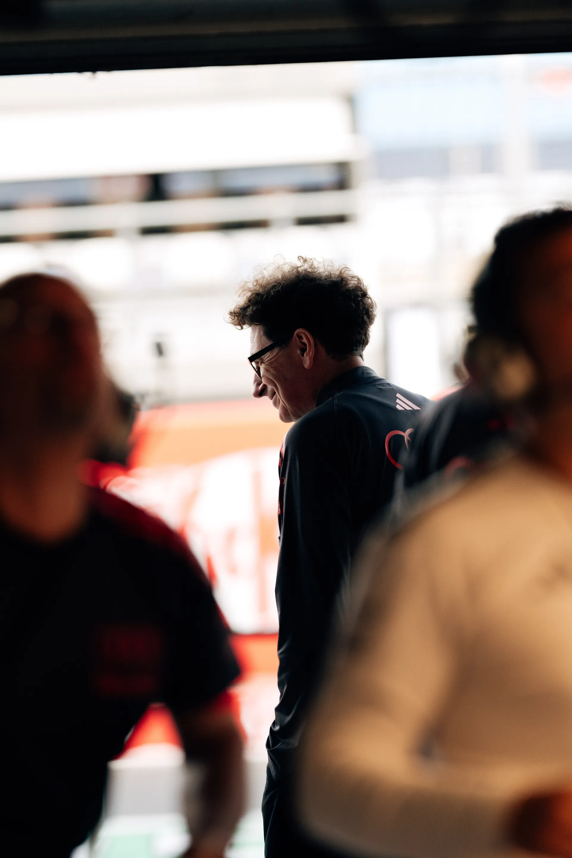 Mattia Binotto of the Audi Revolut F1® Team walks through the garage area, partially obscured by foreground blur.