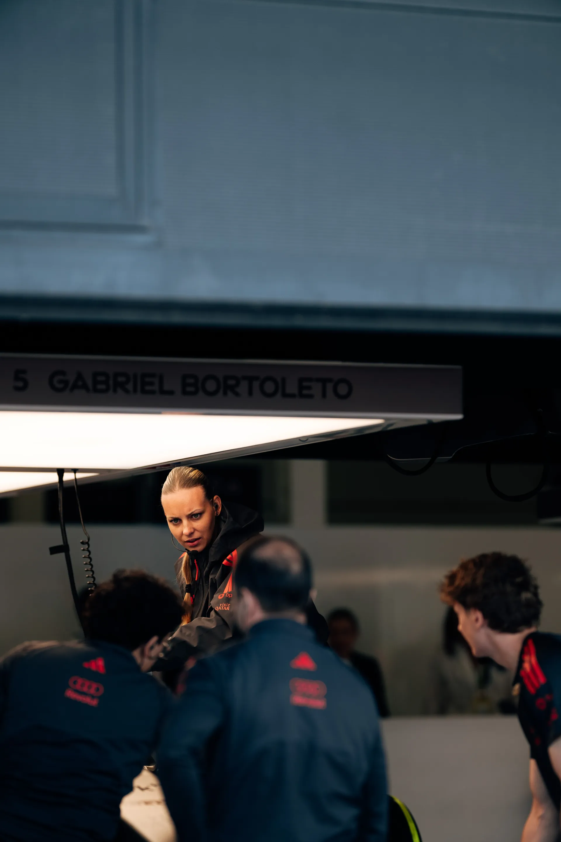 Audi Revolut F1® Team crew gather around Gabriel Bortoleto’s garage bay during a technical discussion.
