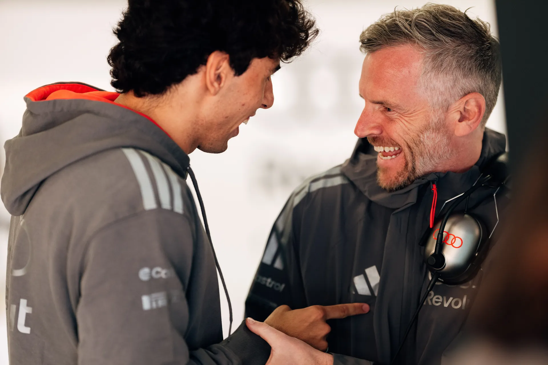Gabriel Bortoleto smiles while speaking with a team member inside the Audi Revolut F1® Team garage.