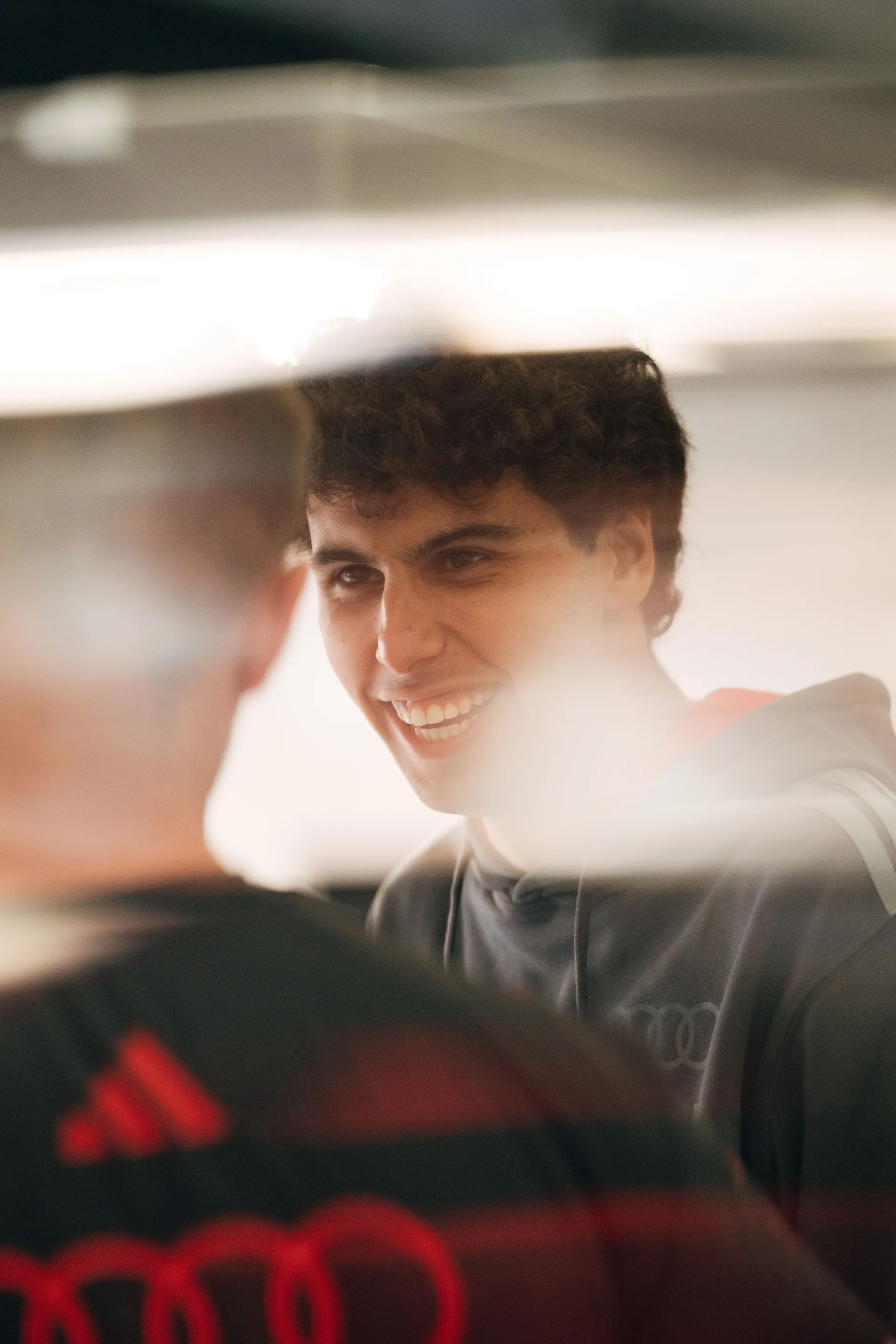 Gabriel Bortoleto laughs with team members during a relaxed moment inside the garage.