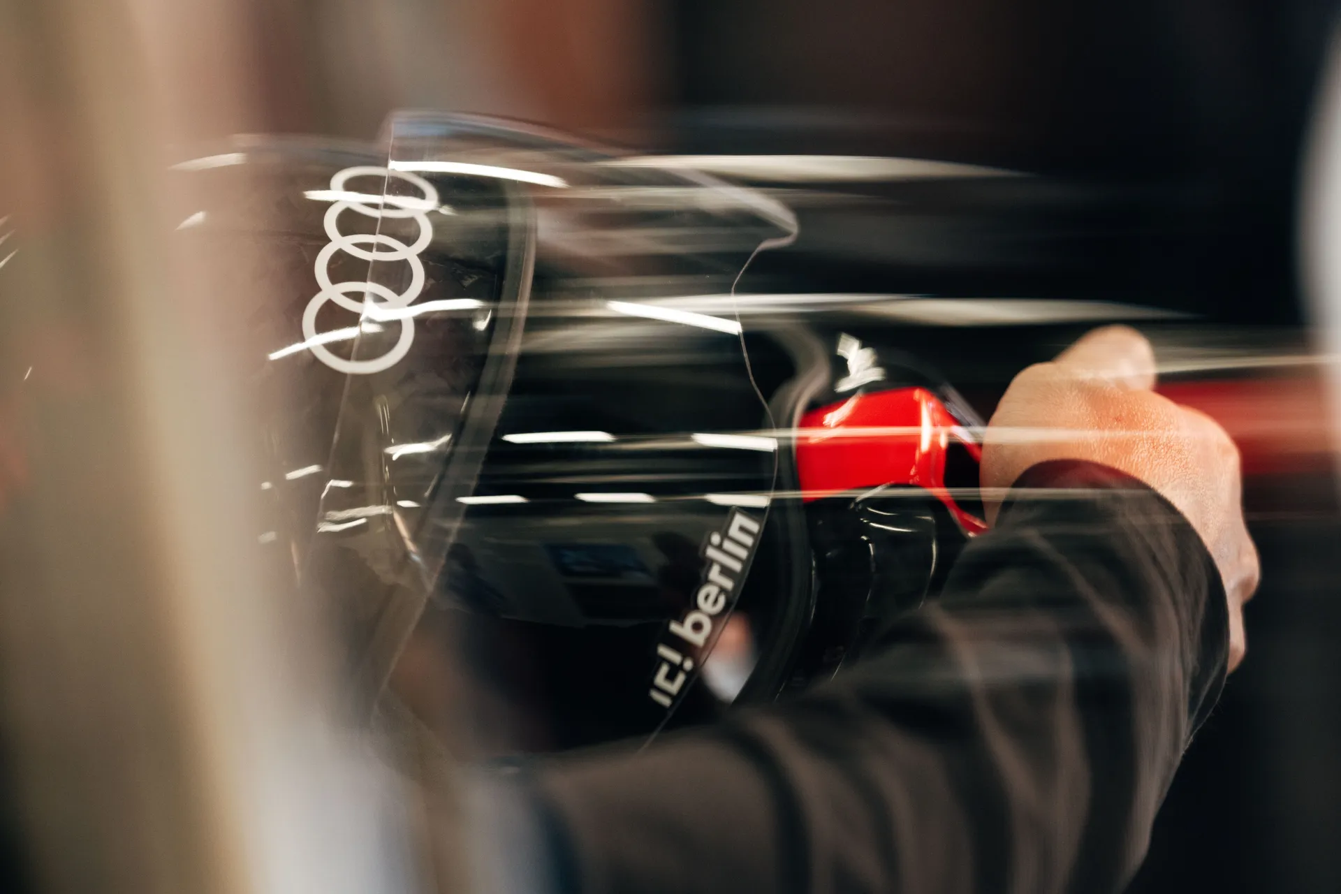 A driver sits inside the cockpit of the Audi R26 as final checks are completed in the garage.