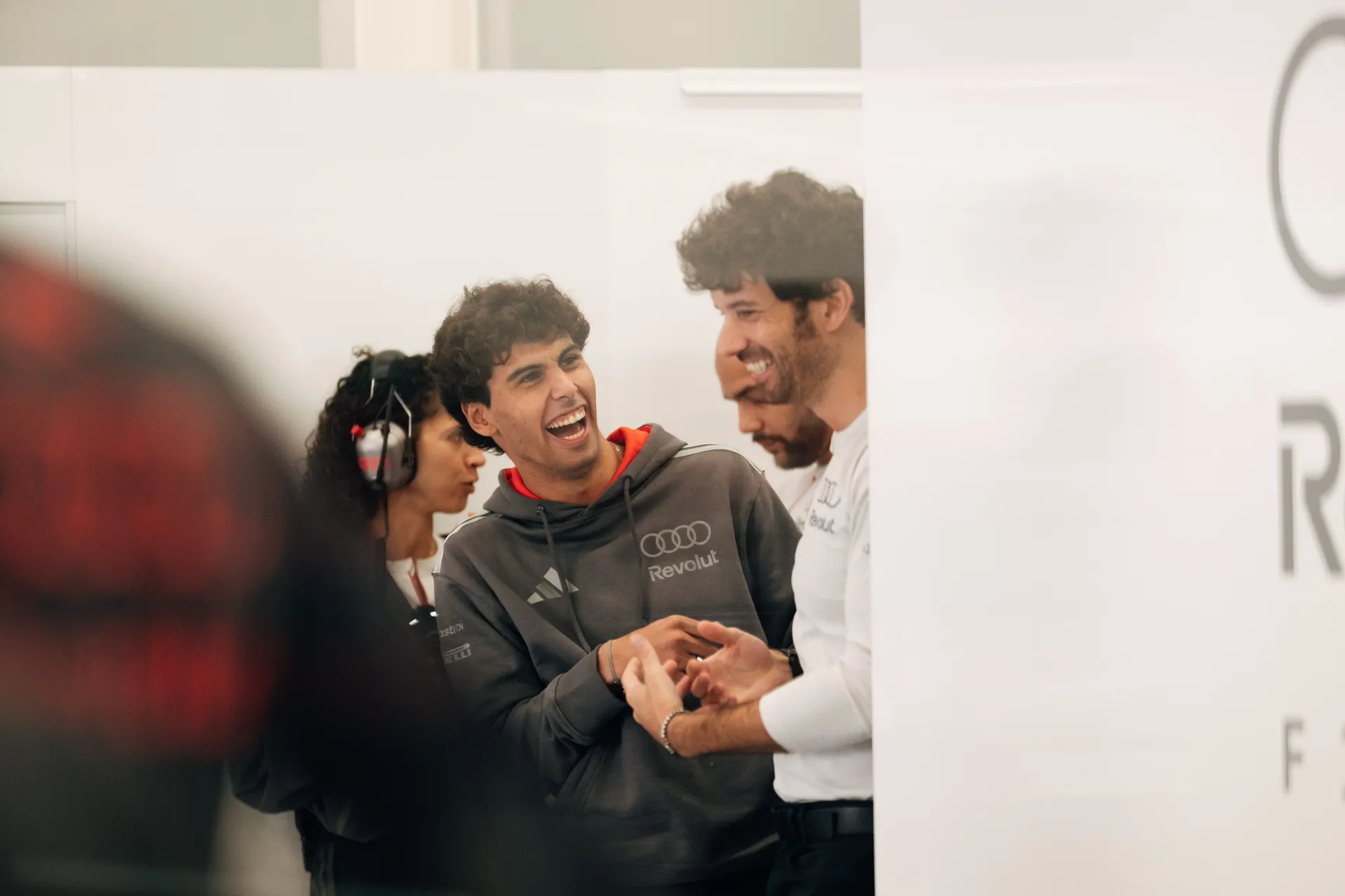 Gabriel Bortoleto laughs with team members during a relaxed moment inside the garage.