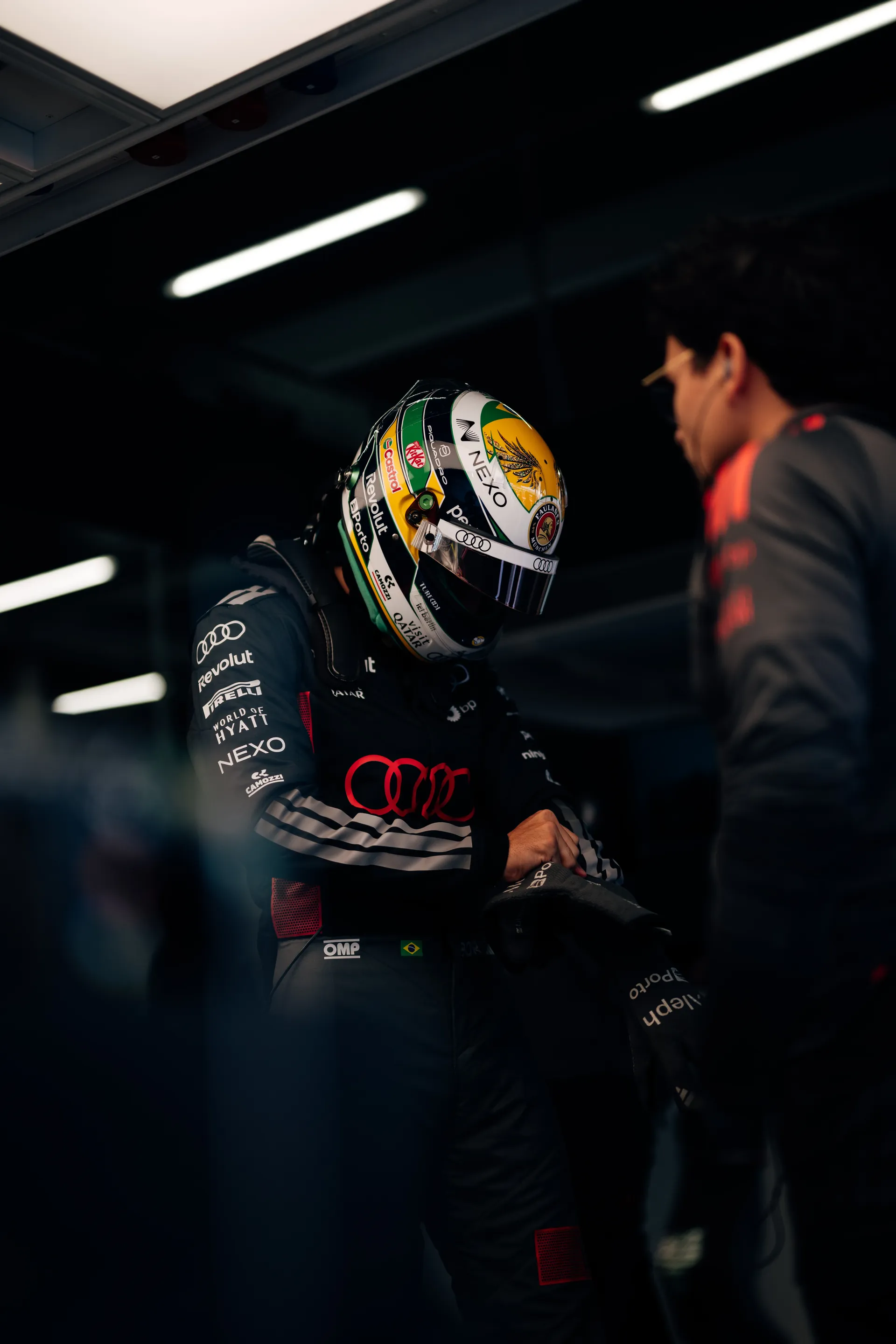 Gabriel Bortoleto adjusts his race gear inside the Audi Revolut F1® Team garage while wearing his helmet.