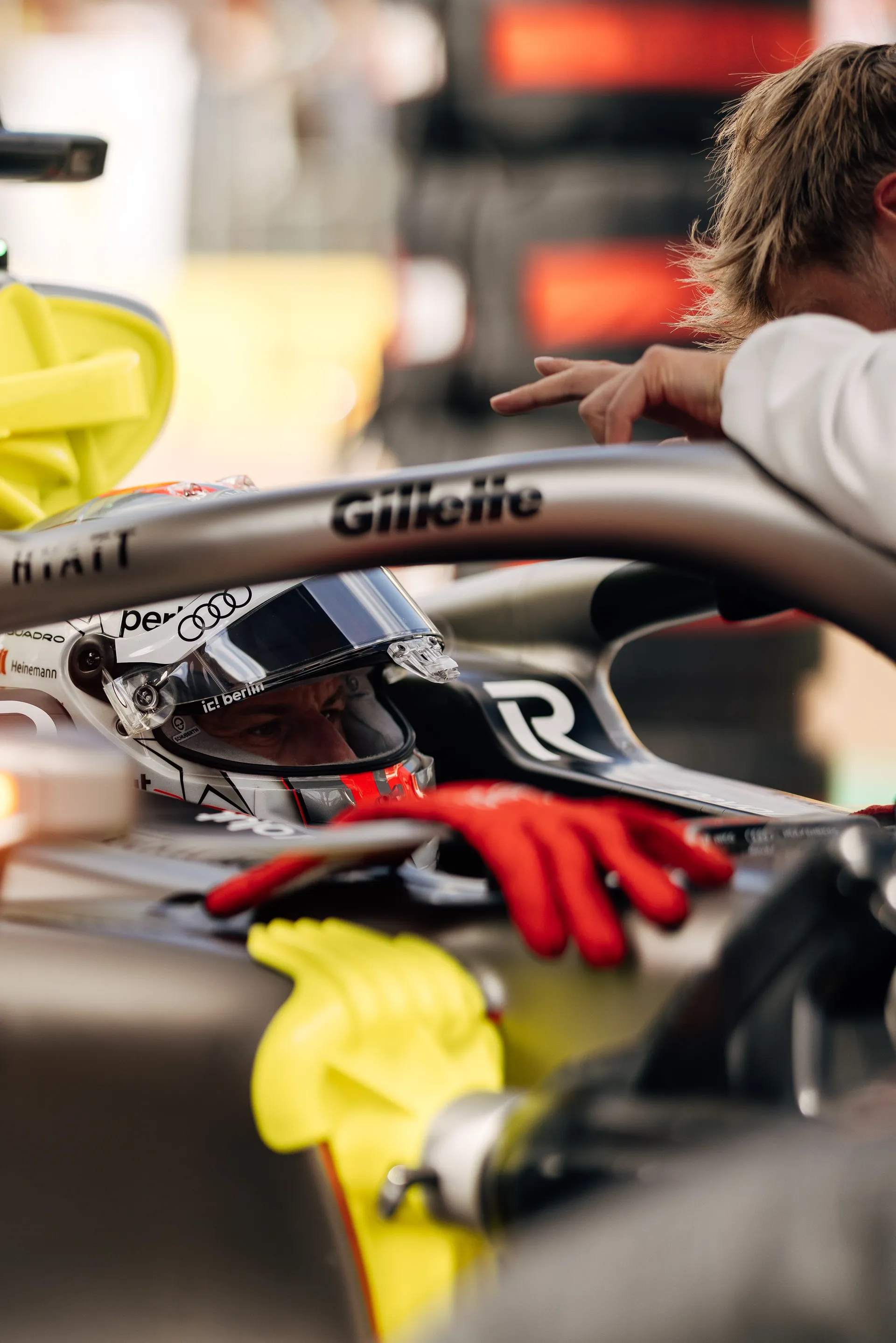 Nico Hulkenberg sits in the Audi Revolut F1® Team car during final preparations as a mechanic leans over the cockpit ahead of the Sprint race in Silverstone.