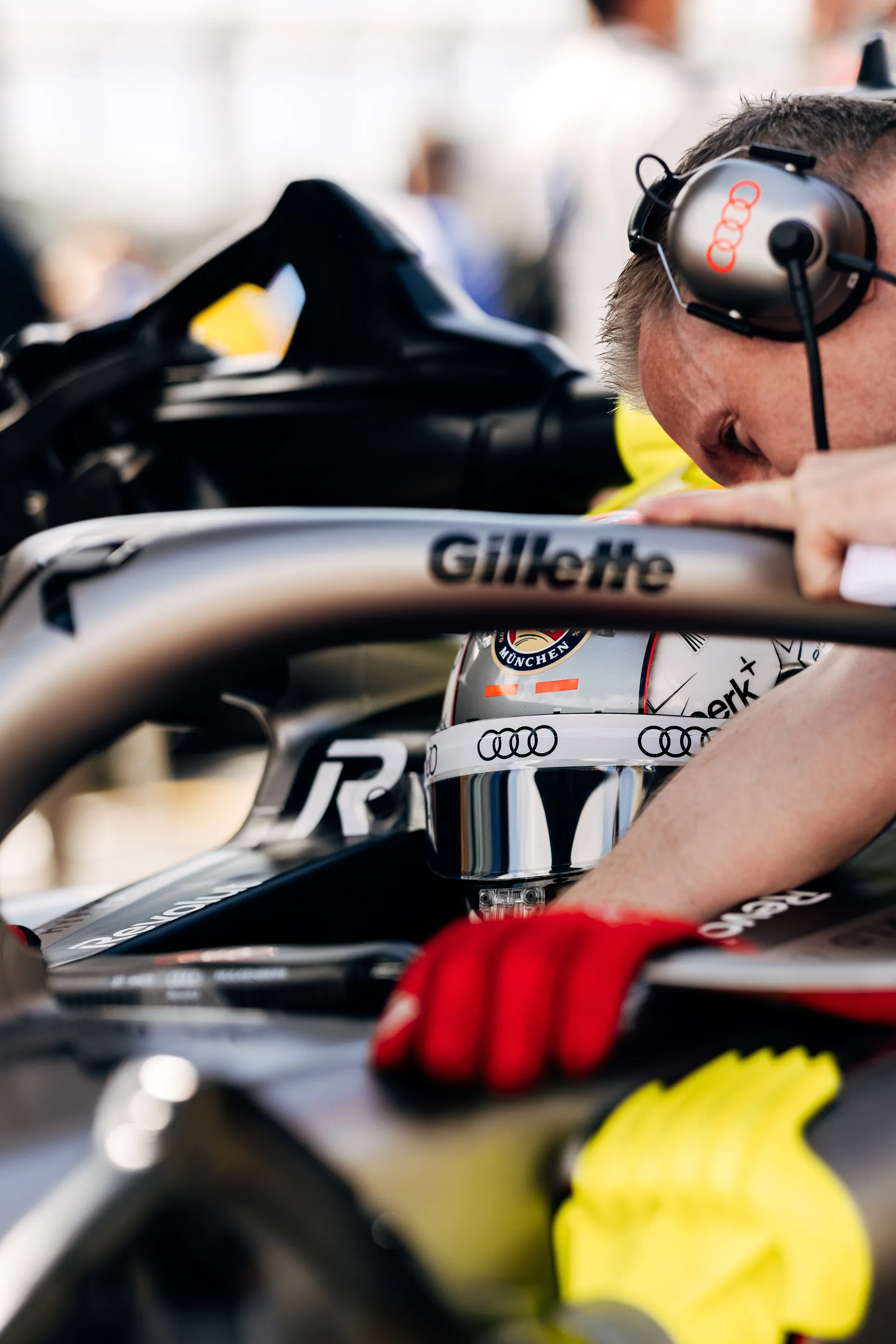 Nico Hulkenberg with a headset checks the cockpit area while the driver remains seated in the Audi Revolut F1® Team car before the Sprint race.
