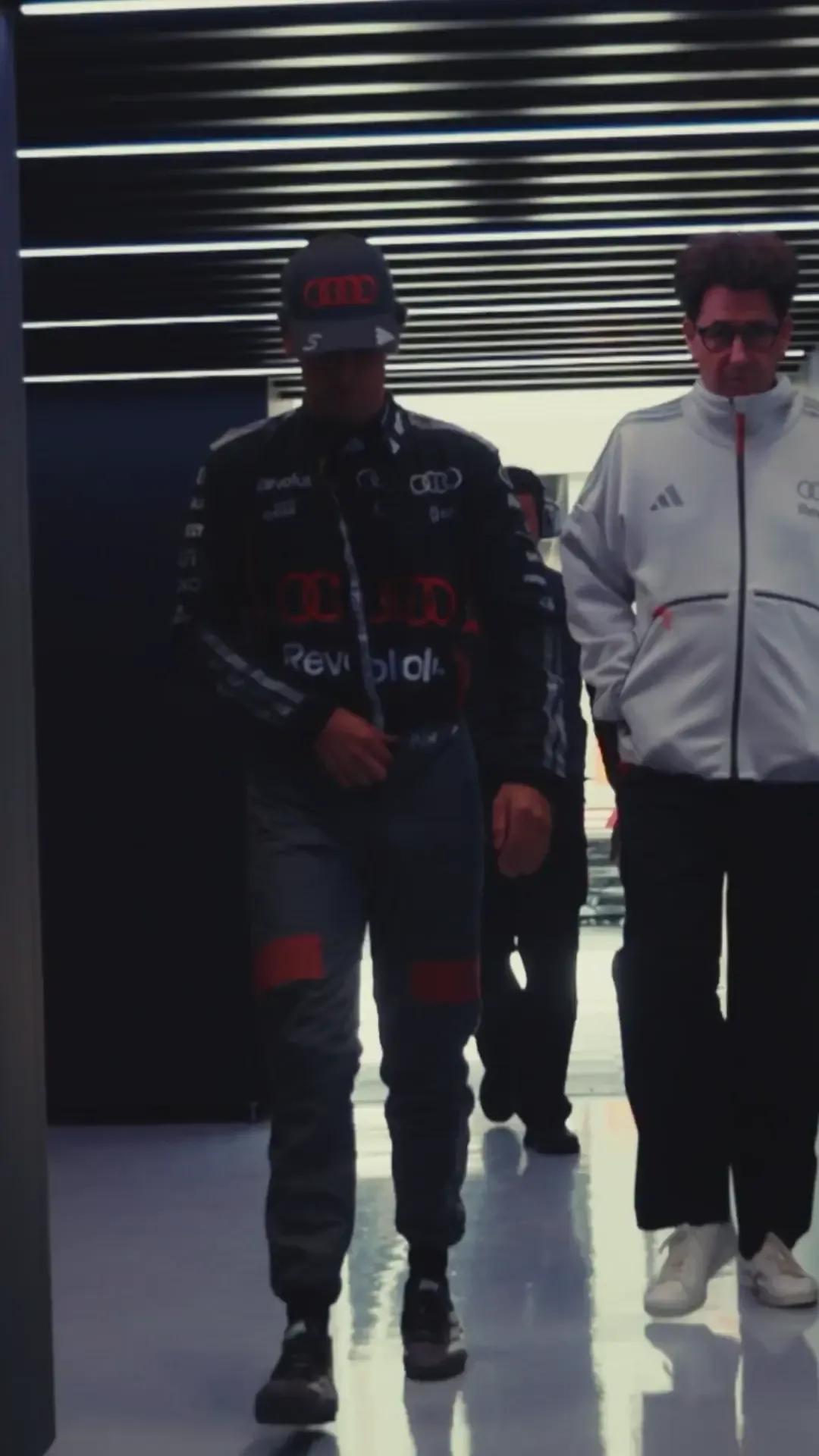 Gabriel Bortoleto climbs into the Audi Revolut F1® Team car in the garage, preparing for the Sprint race at Silverstone as crew members complete final checks around the cockpit.