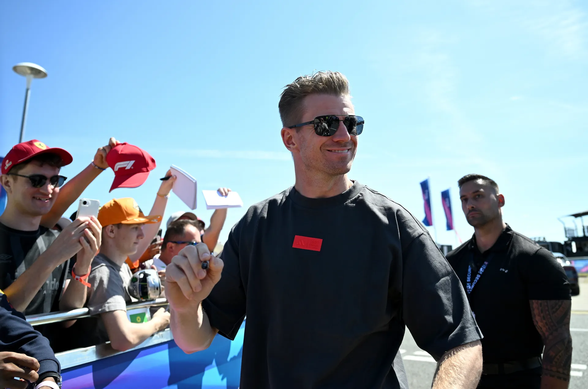 Nico Hulkenberg smiles and signs autographs for fans along the paddock barrier at the British Grand Prix.