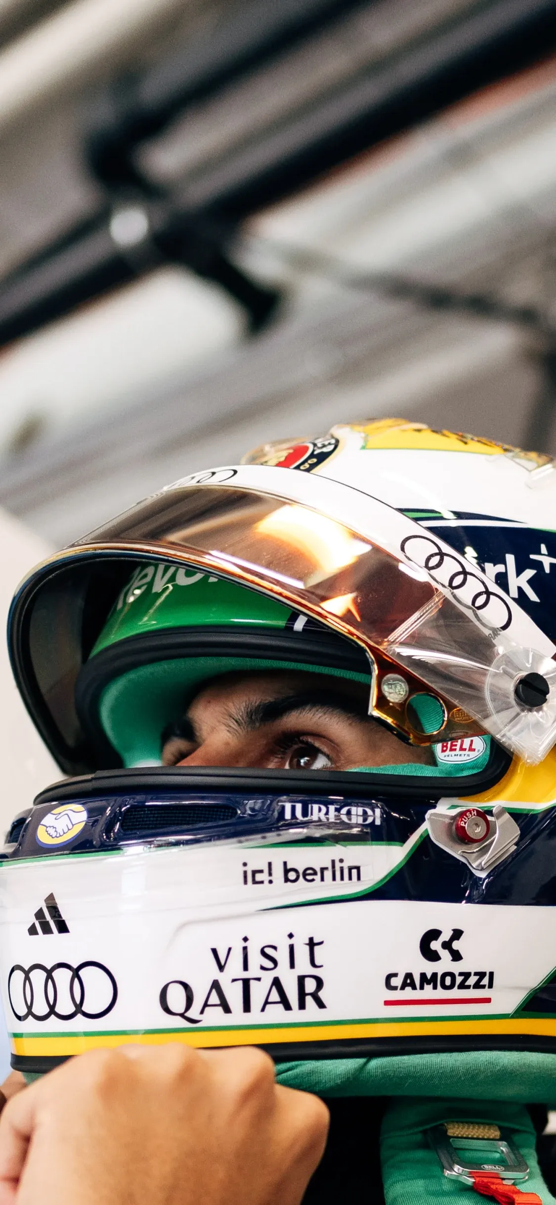 Close-up of an Audi Revolut F1® Team driver adjusting his helmet, visor down and eyes focused ahead before heading out on track.