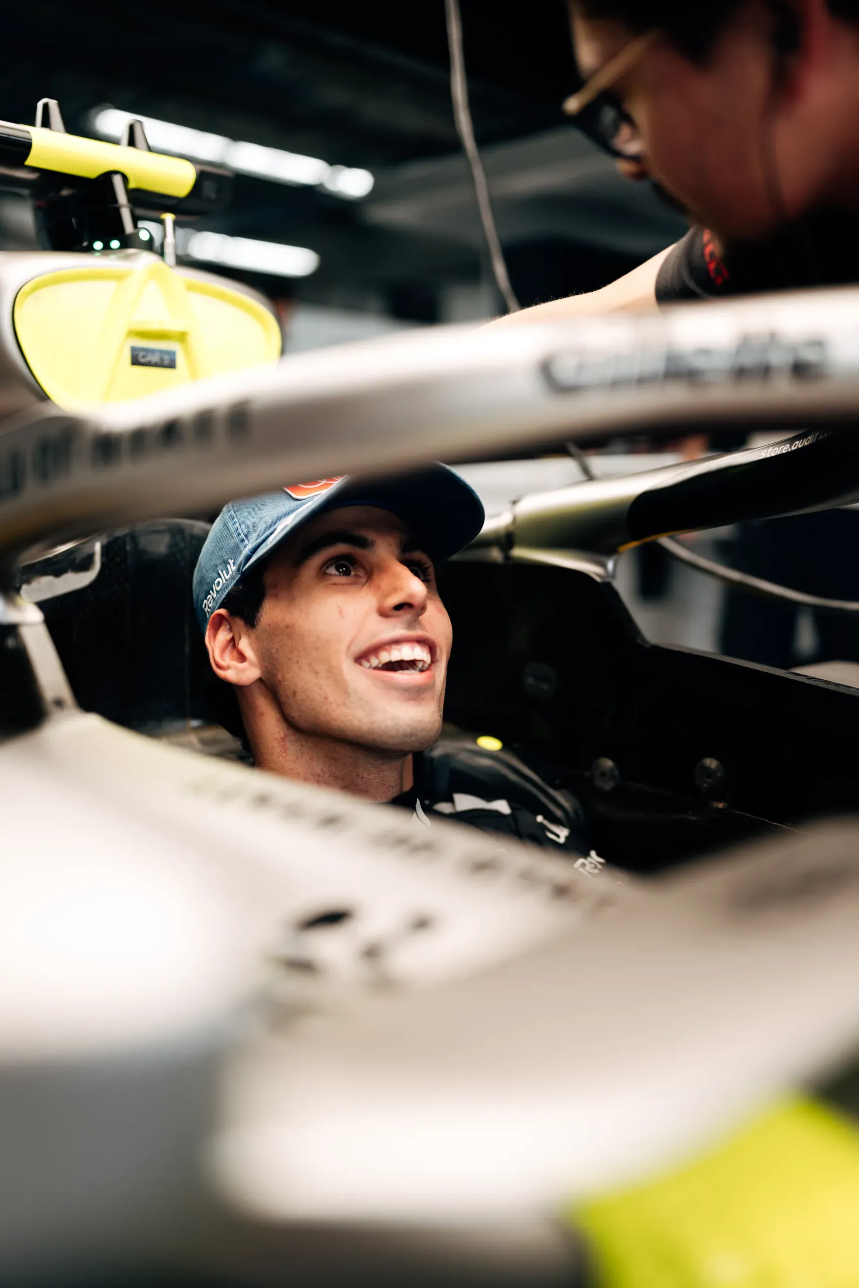 Audi Revolut F1® Team driver Gabriel Bortoleto smiling in the cockpit of the Audi R26 as a mechanic leans in