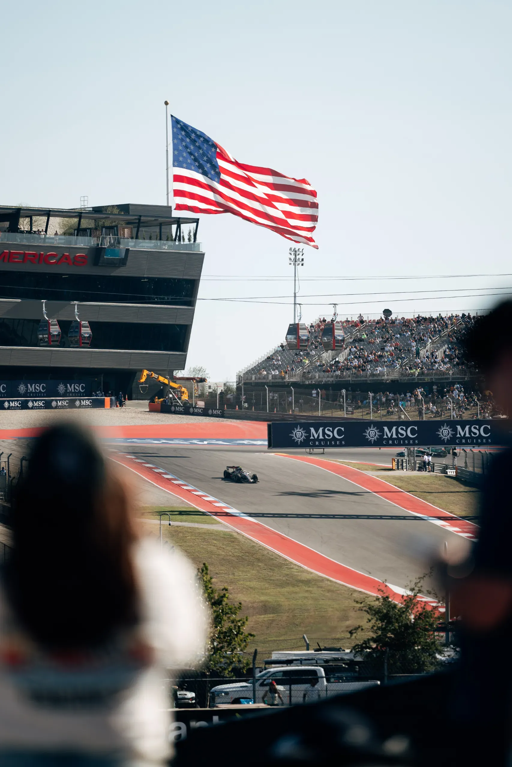 Audi R26 of the Audi Revolut F1® Team on track below a giant US flag at the United States Grand Prix