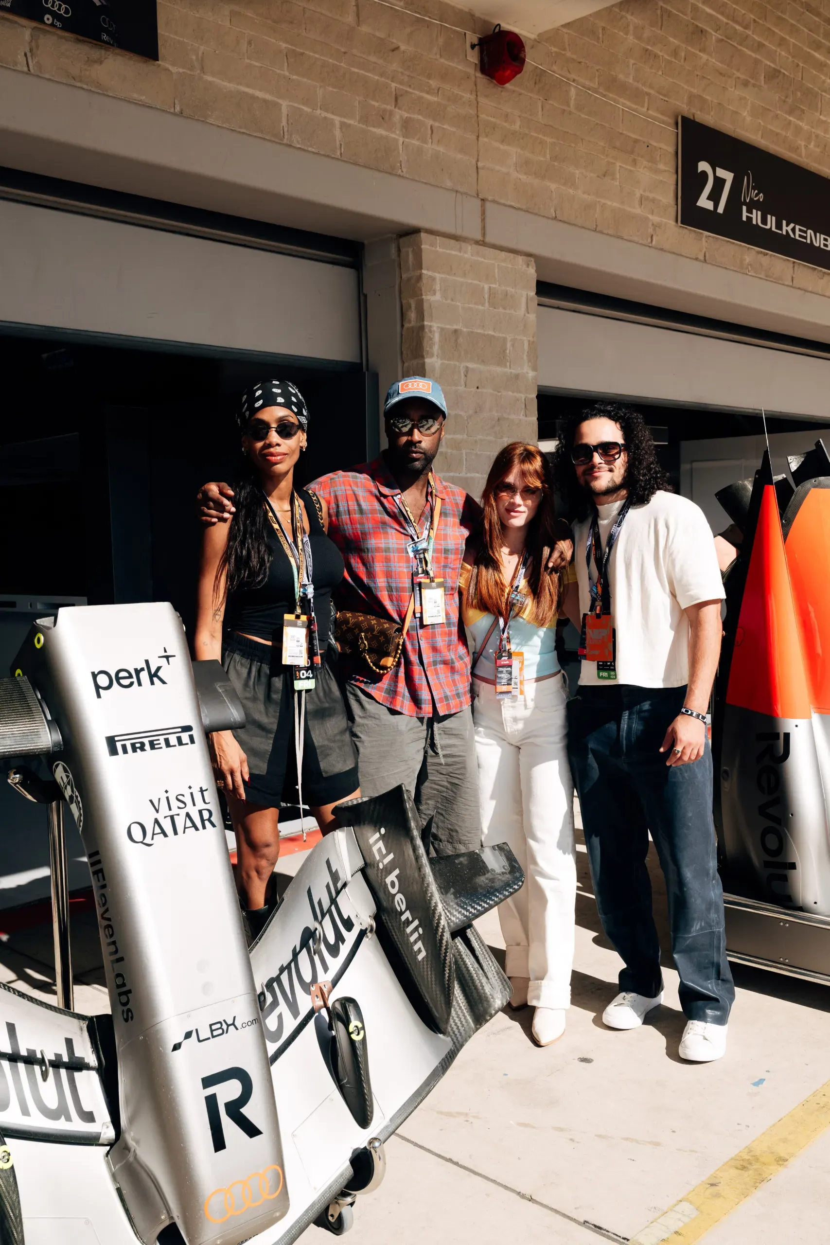 Four guests pose by a rear wing outside the Audi Revolut F1® Team garage at the United States Grand Prix