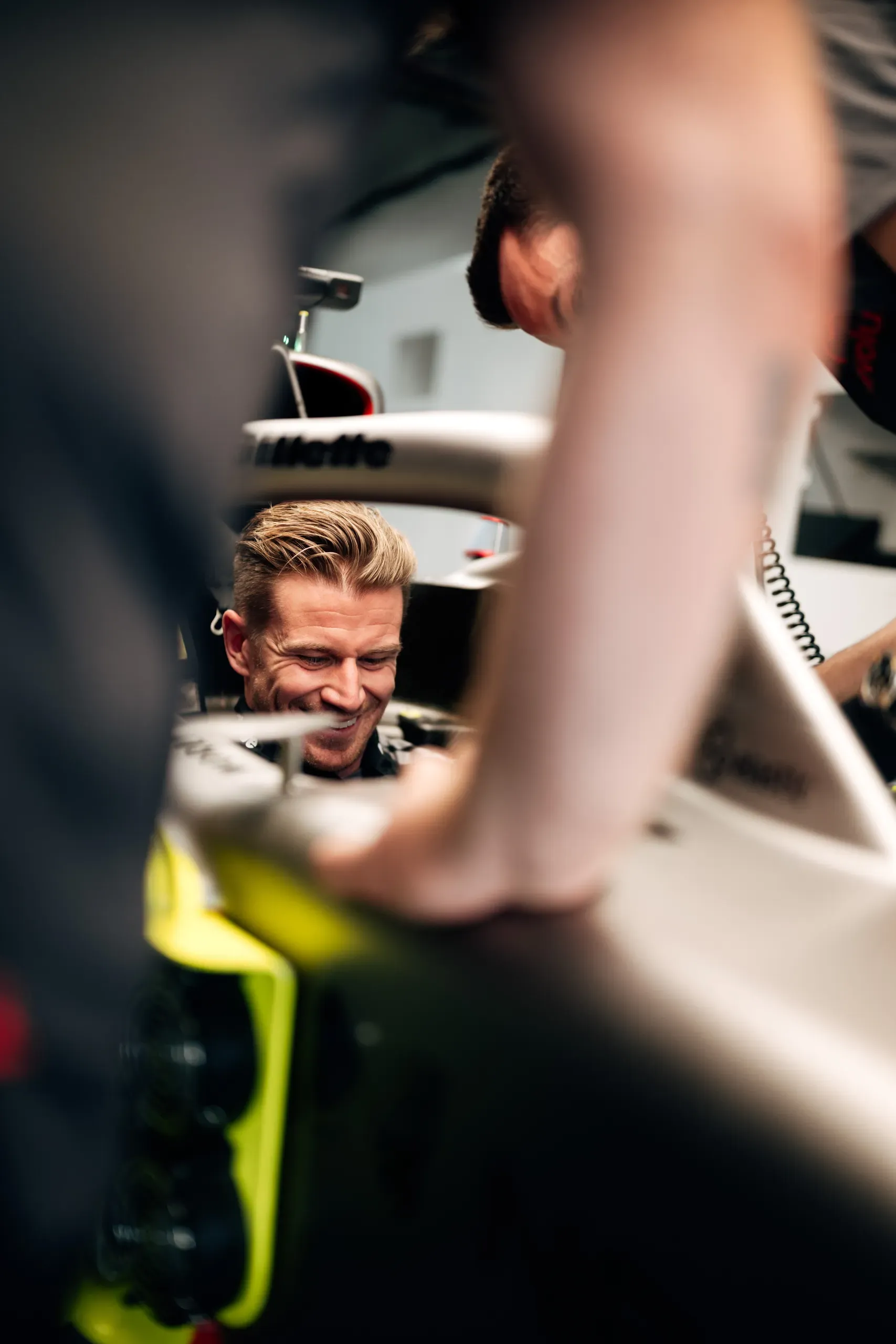 Audi Revolut F1® Team driver Nico Hulkenberg smiling in the cockpit of the Audi R26 as team members lean in