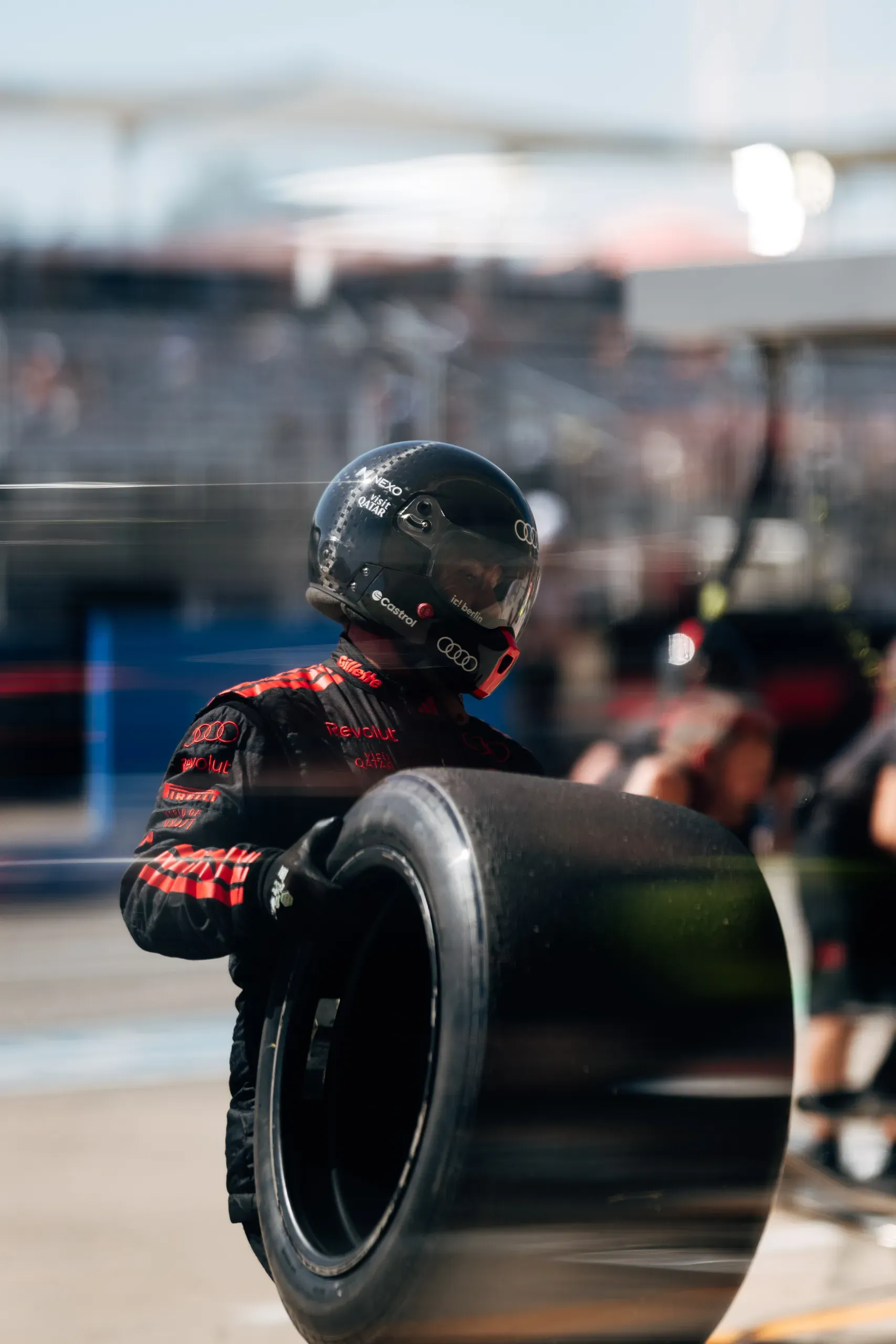 A mechanic of the Audi Revolut F1® Team in a pit crew helmet carrying a tyre in the pit lane at the United States Grand Prix