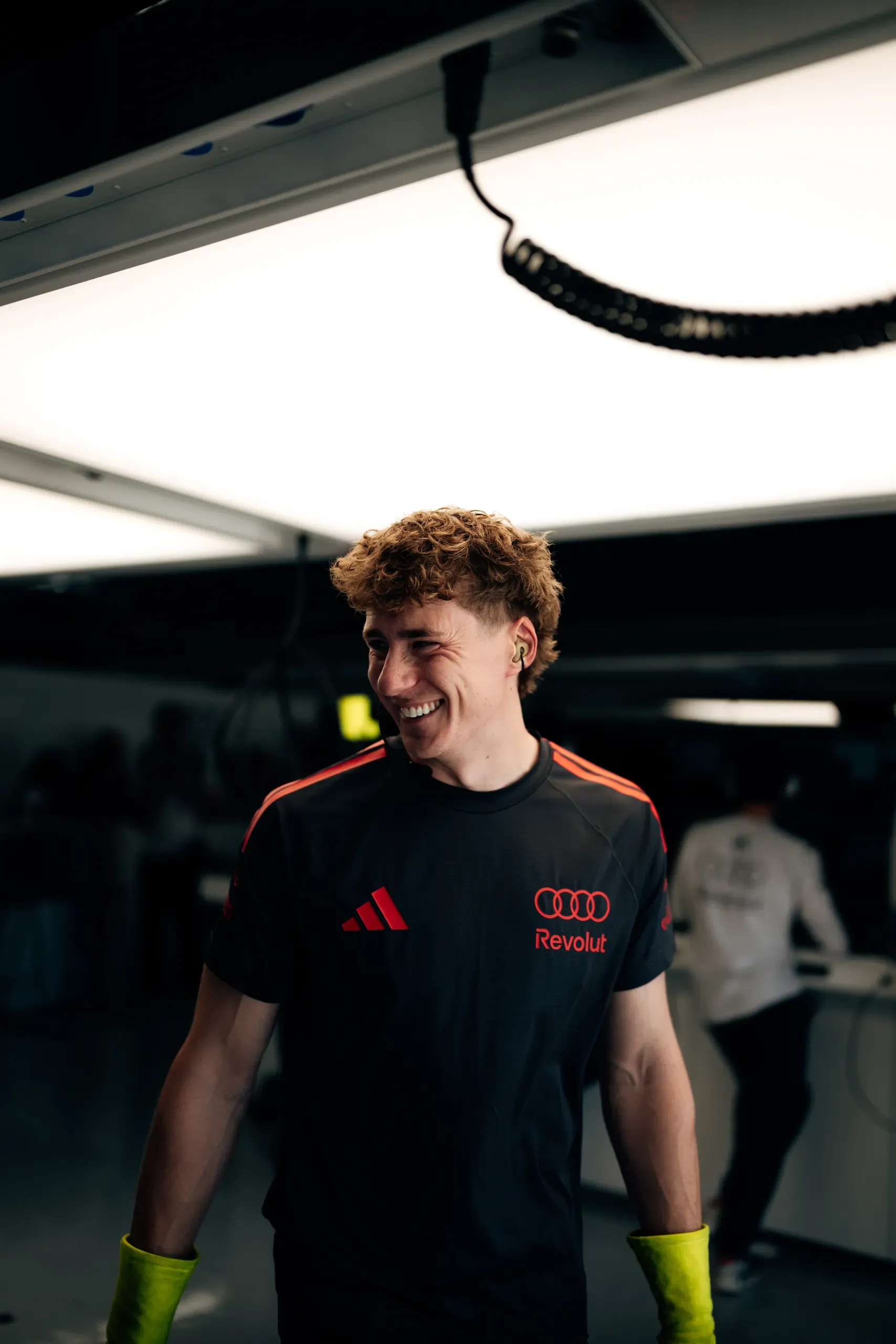 A smiling Audi Revolut F1® Team member with curly hair in the garage at the United States Grand Prix