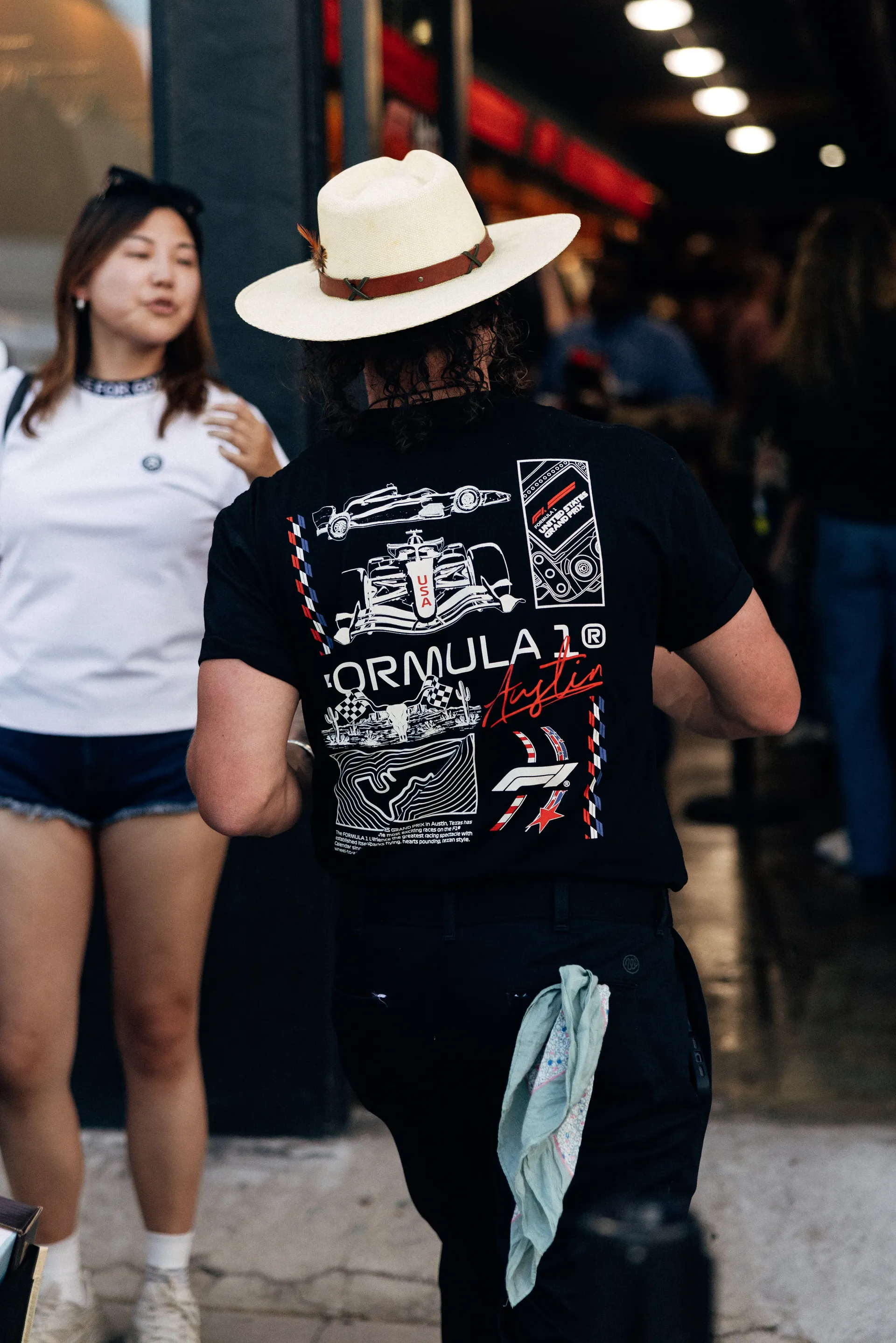 Fan in a straw cowboy hat wearing an F1® Austin T-shirt on the street at the United States Grand Prix
