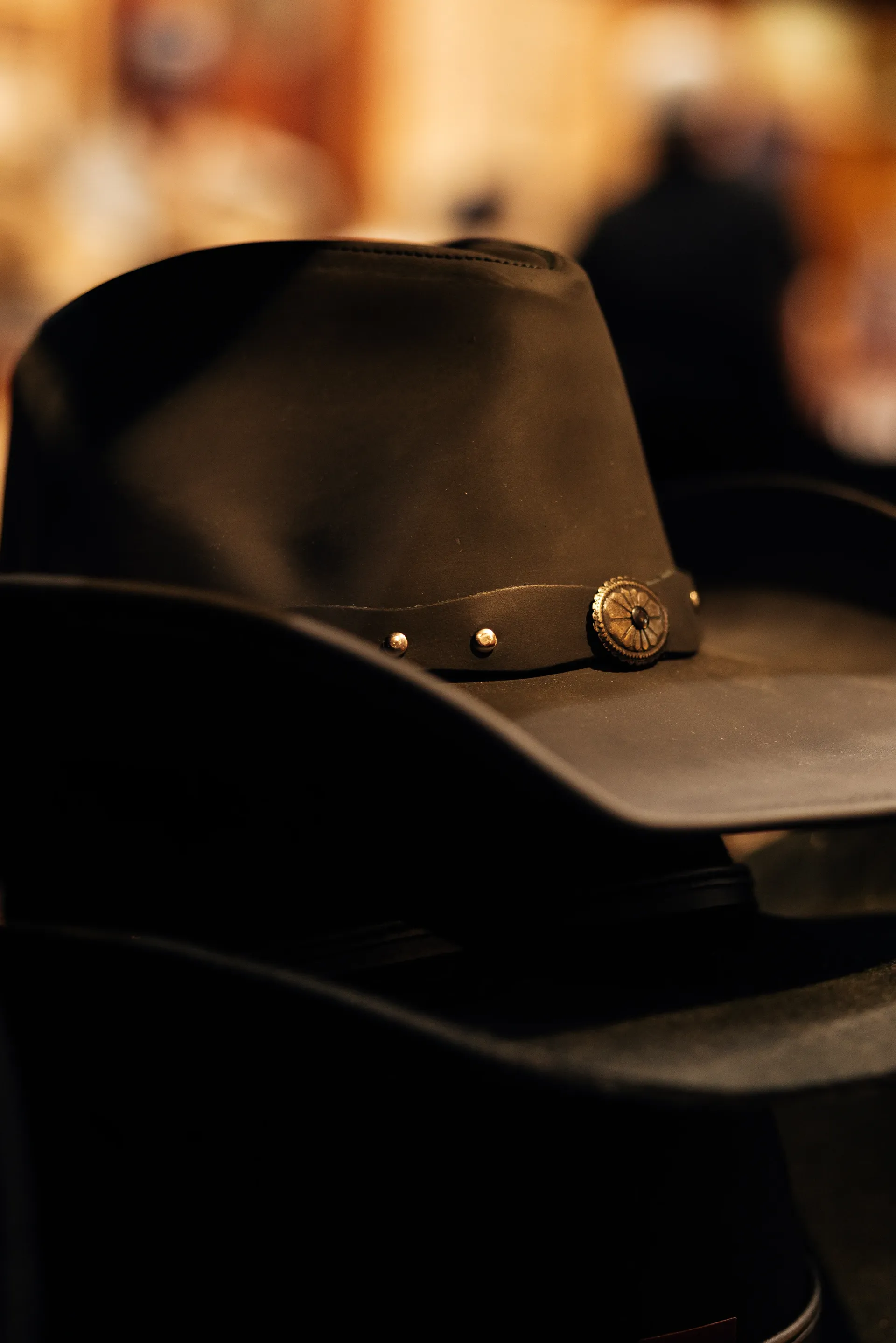 Close-up of a black leather cowboy hat with a silver concho band in a Western store in Austin