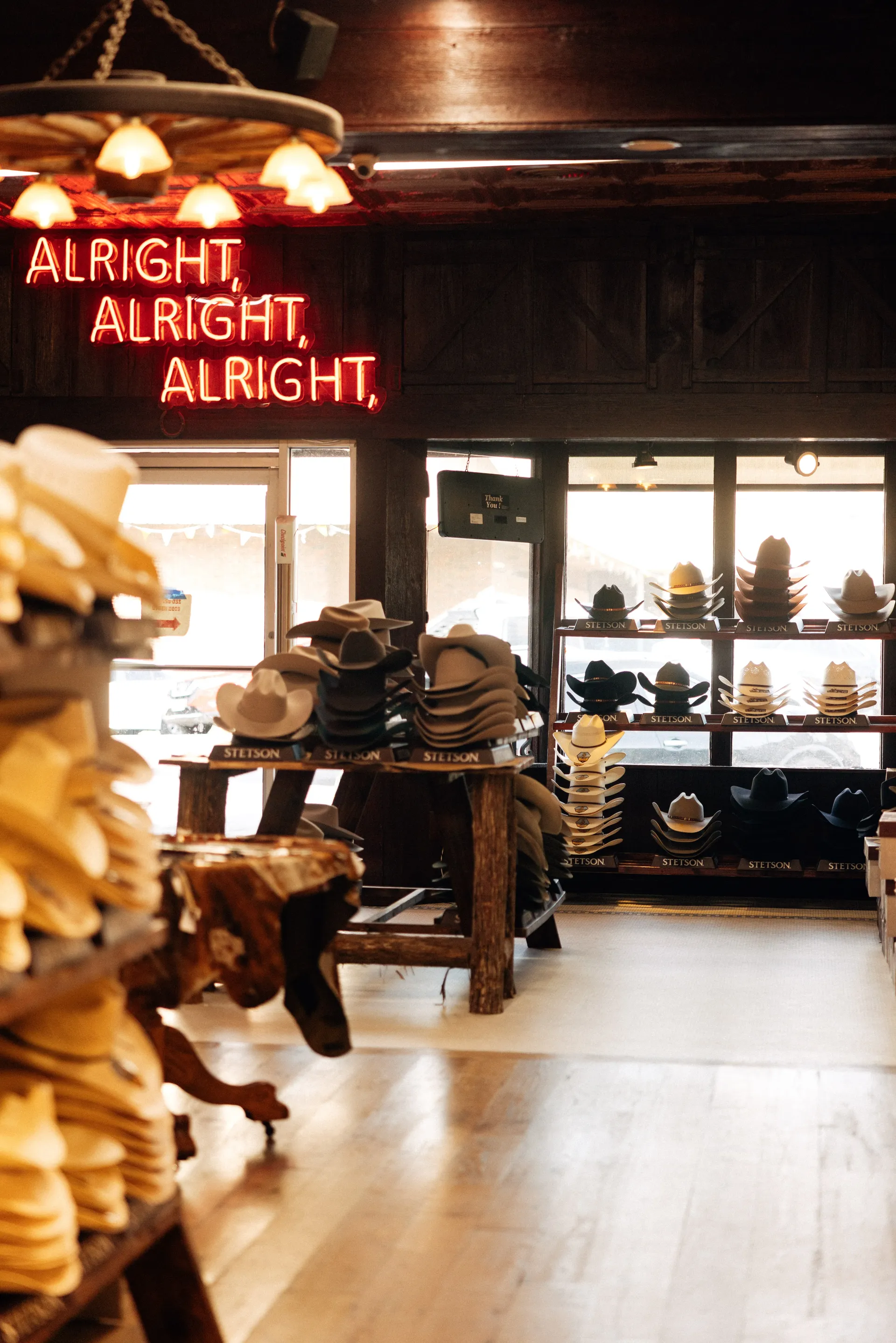 Stetson cowboy hats on display under a red neon sign reading Alright, Alright, Alright in Austin