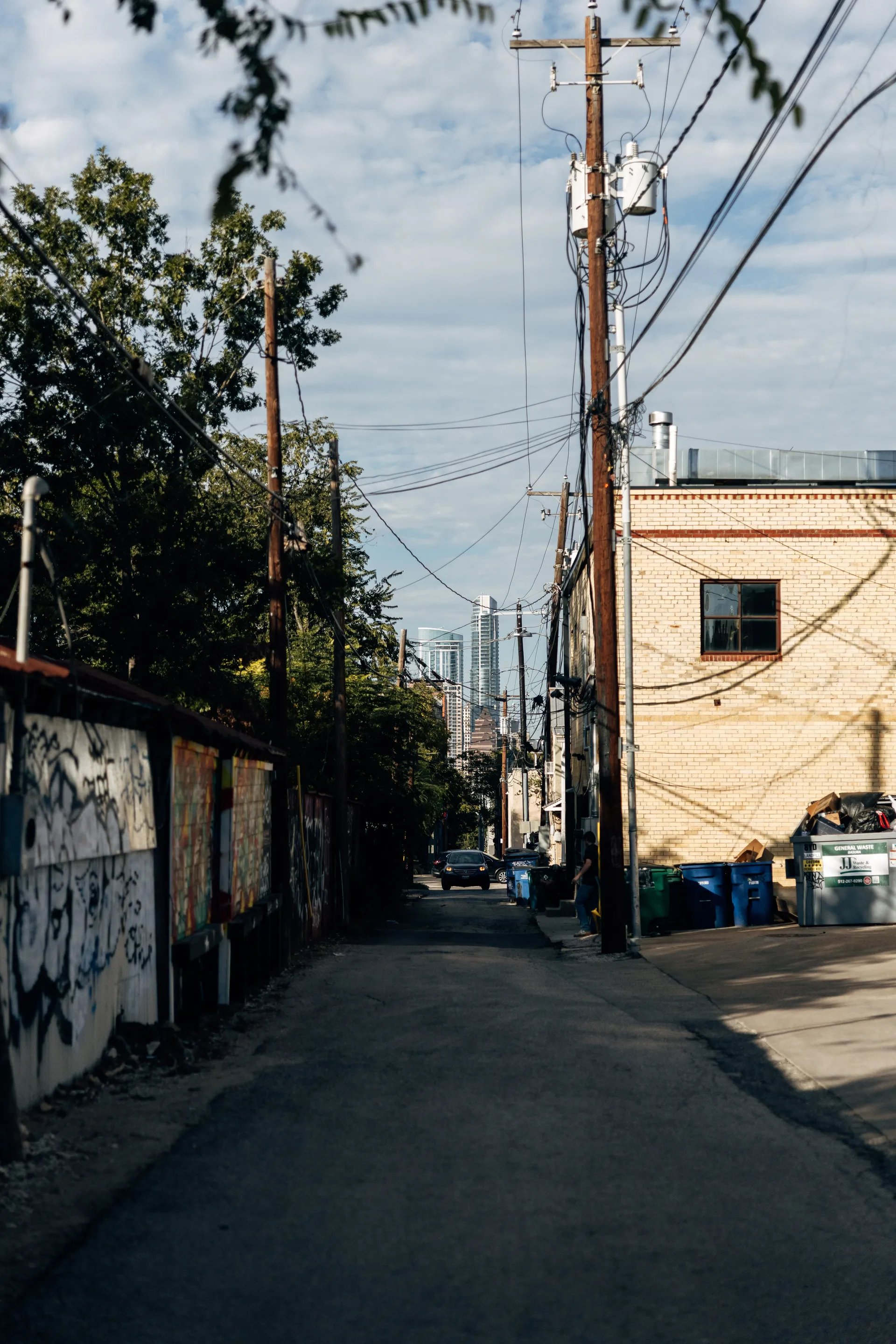 Back alley with graffiti walls and power lines leading towards the Austin skyline, United States Grand Prix