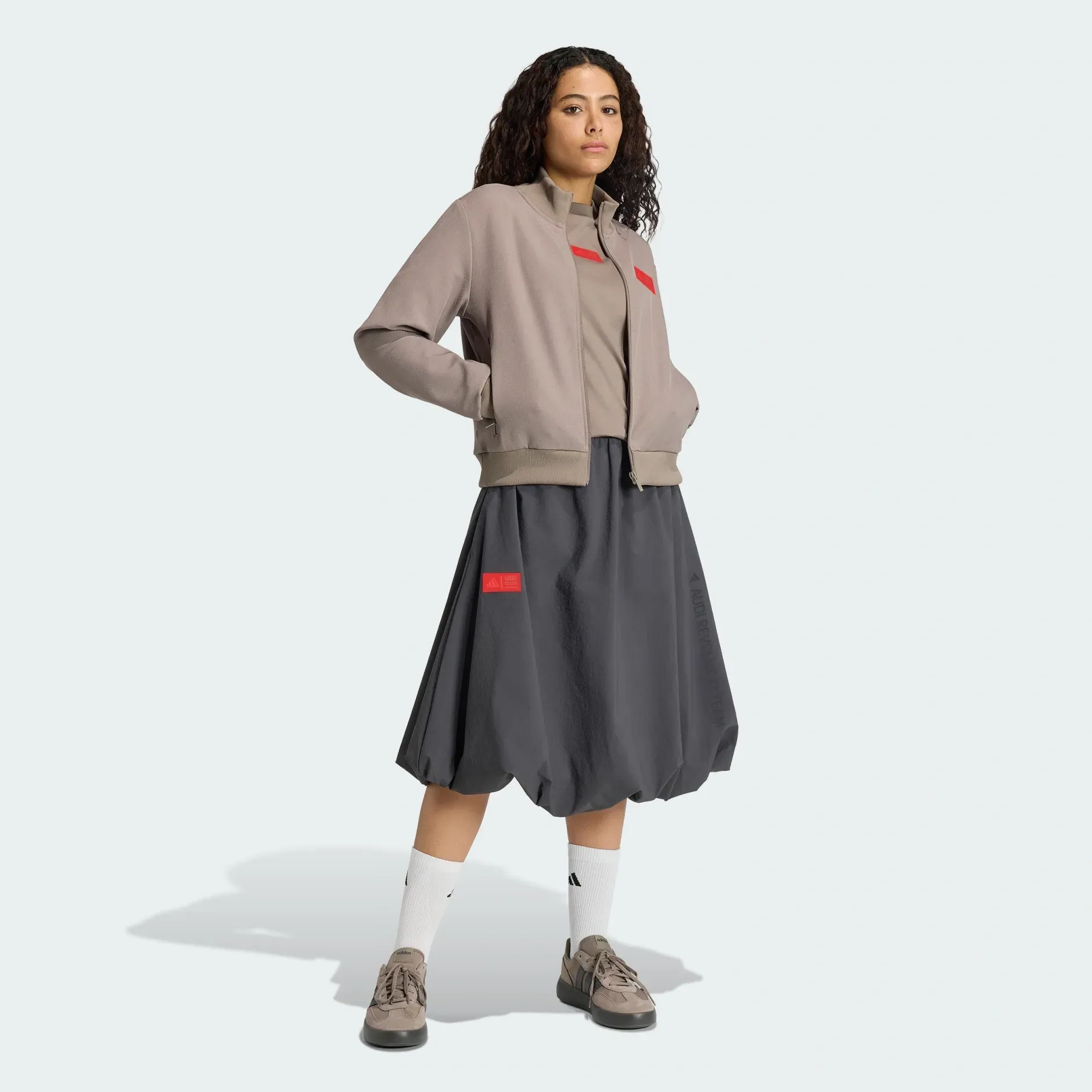 Young female model wearing adidas x Audi Revolut F1® Team fanwear elevated woven skirt in the Studio