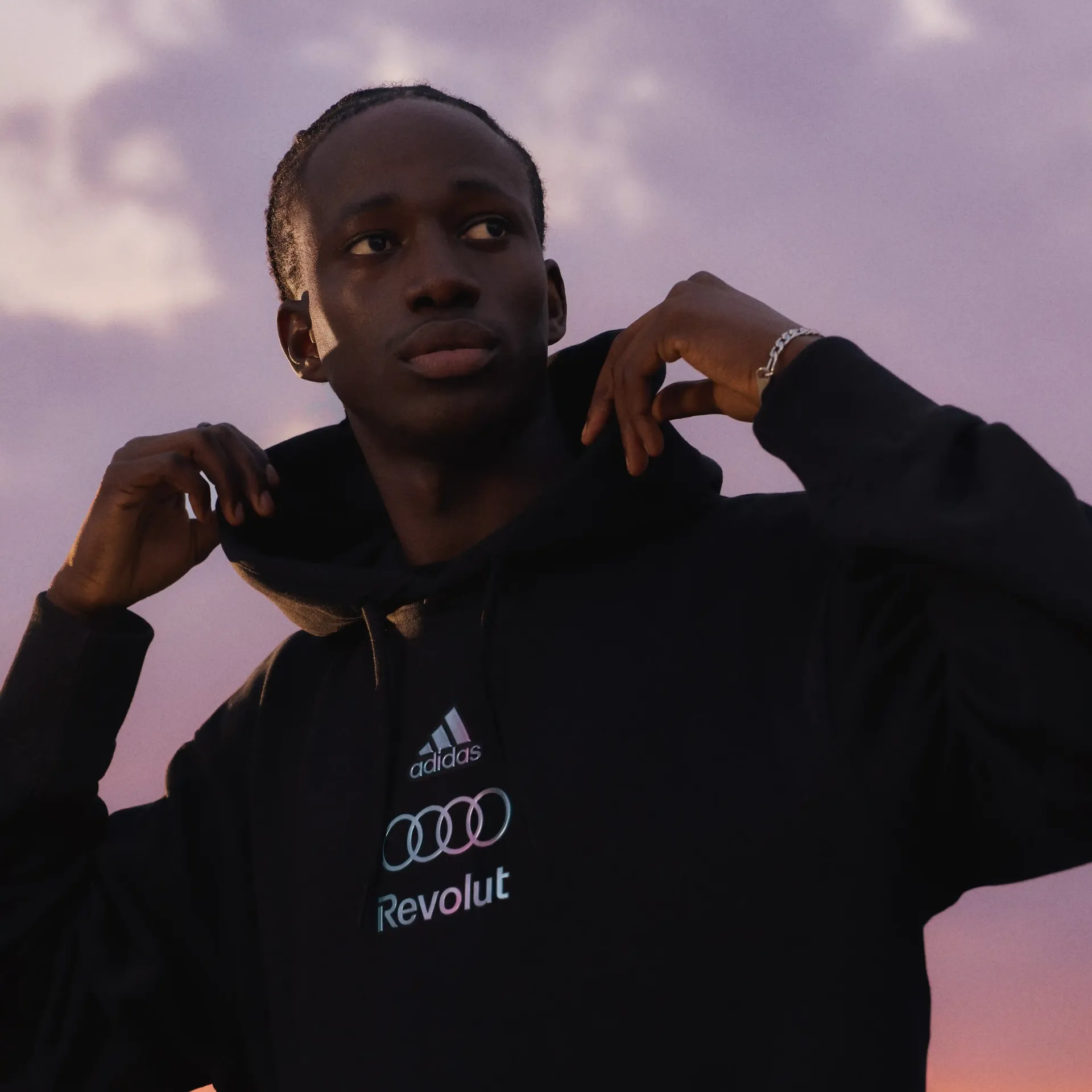 Close-up portrait of male model adjusting collar wearing adidas performance fanwear hoddie