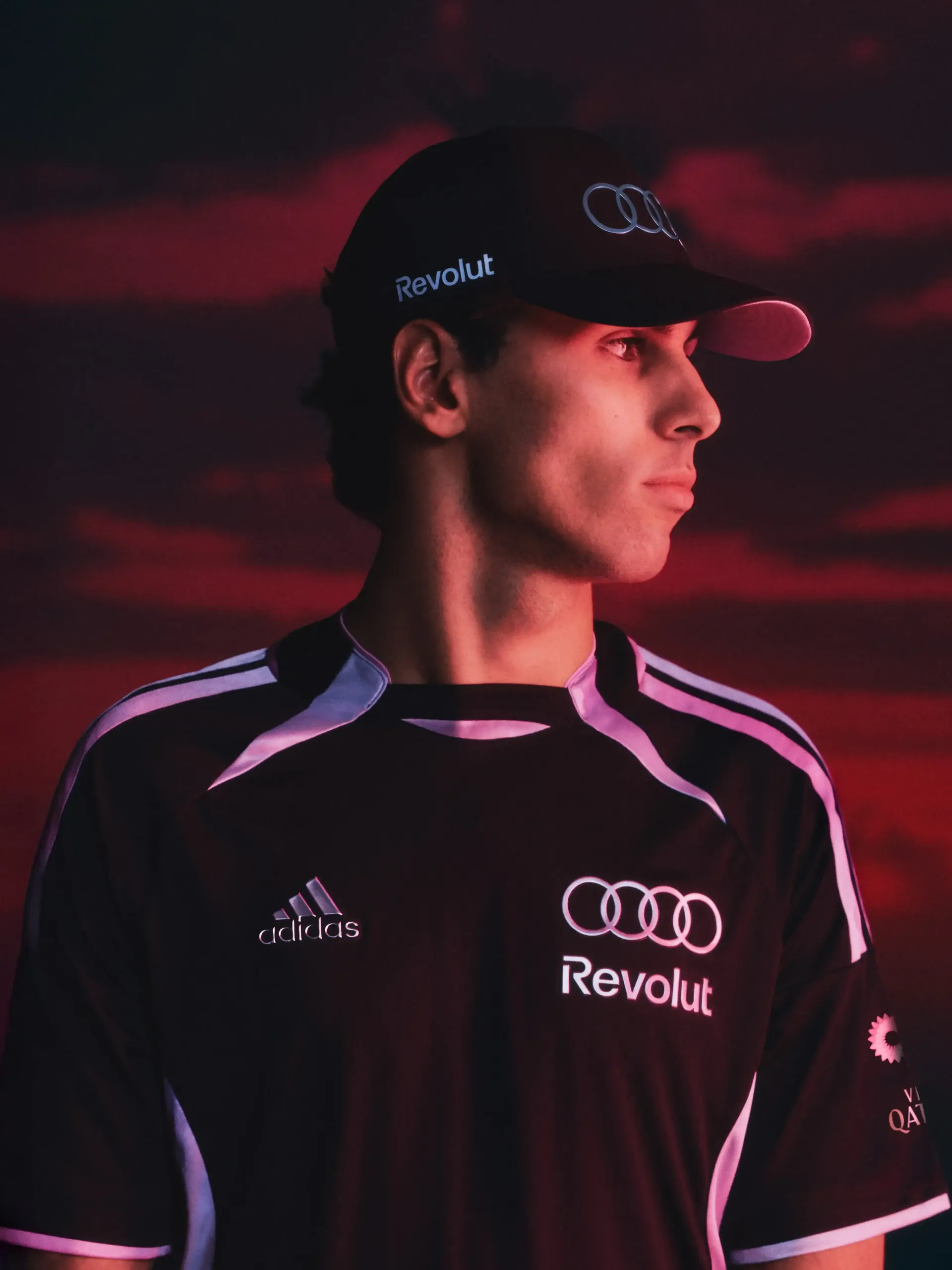 Portrait of Gabriel Bortoleto, athlete of the Audi Revolut F1® Team wearing teamwear outfit with dramatic red background lighting