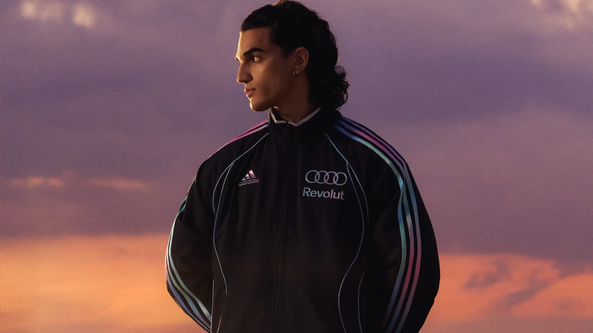Young male model standing in a confident pose, wearing adidas performance teamwear outfit with sundown in the background