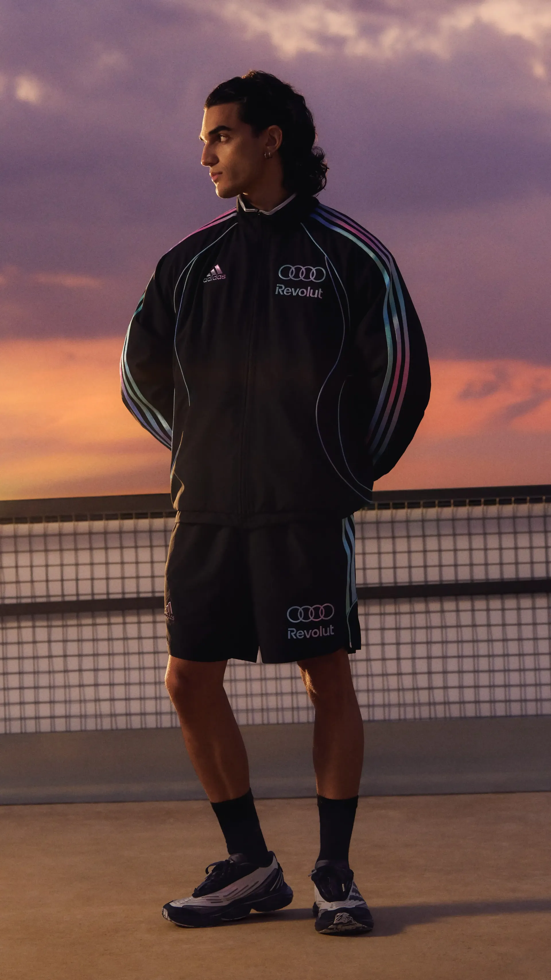 Young male model standing in a confident pose, wearing adidas performance teamwear outfit with sundown in the background