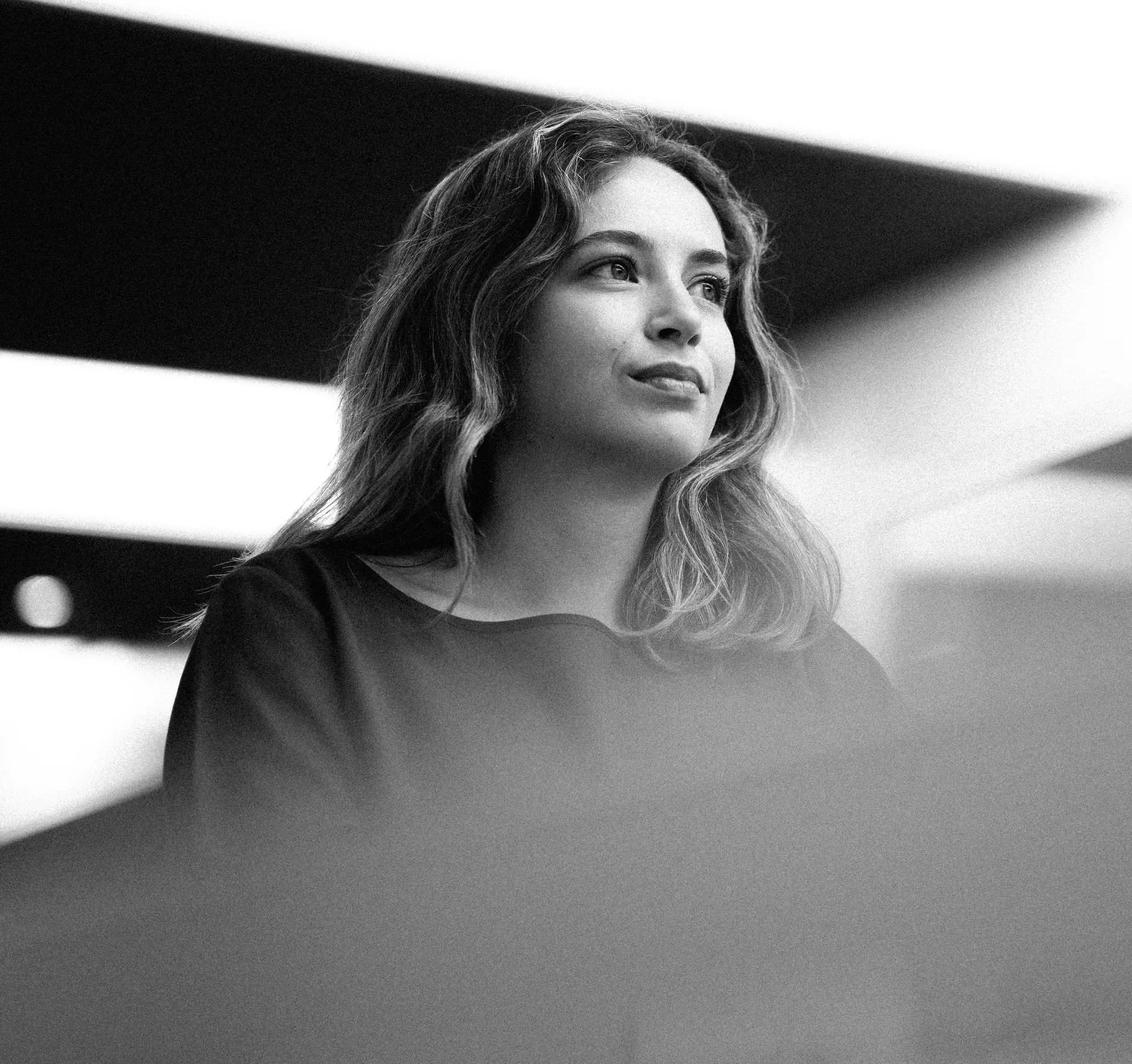 Black-and-white close-up of Sofia Rodrigues, Junior Cost Cap Analyst at the Audi Revolut F1 Team, looking thoughtfully into the distance.