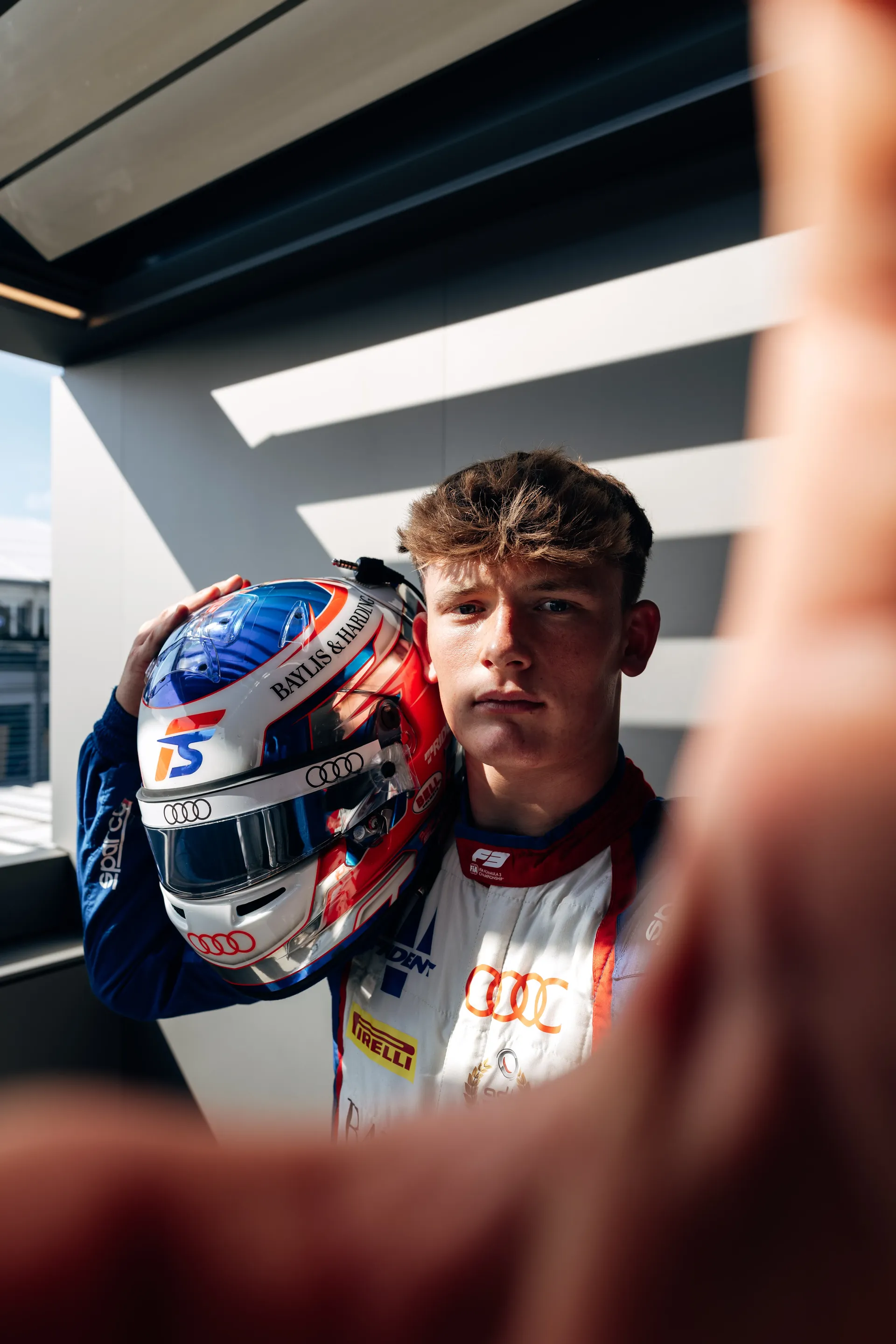 Close up of Audi Revolut F1® Team Academy F3 driver Freddie Slater holding his helmet on the shoulder