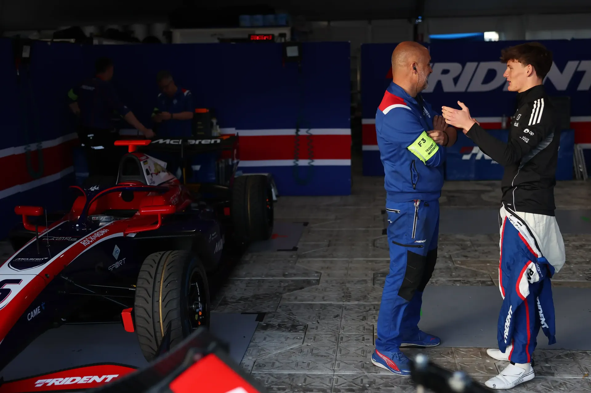 Audi Revolut F1® Team Academy driver Freddie slater discussing strategy inside the garage