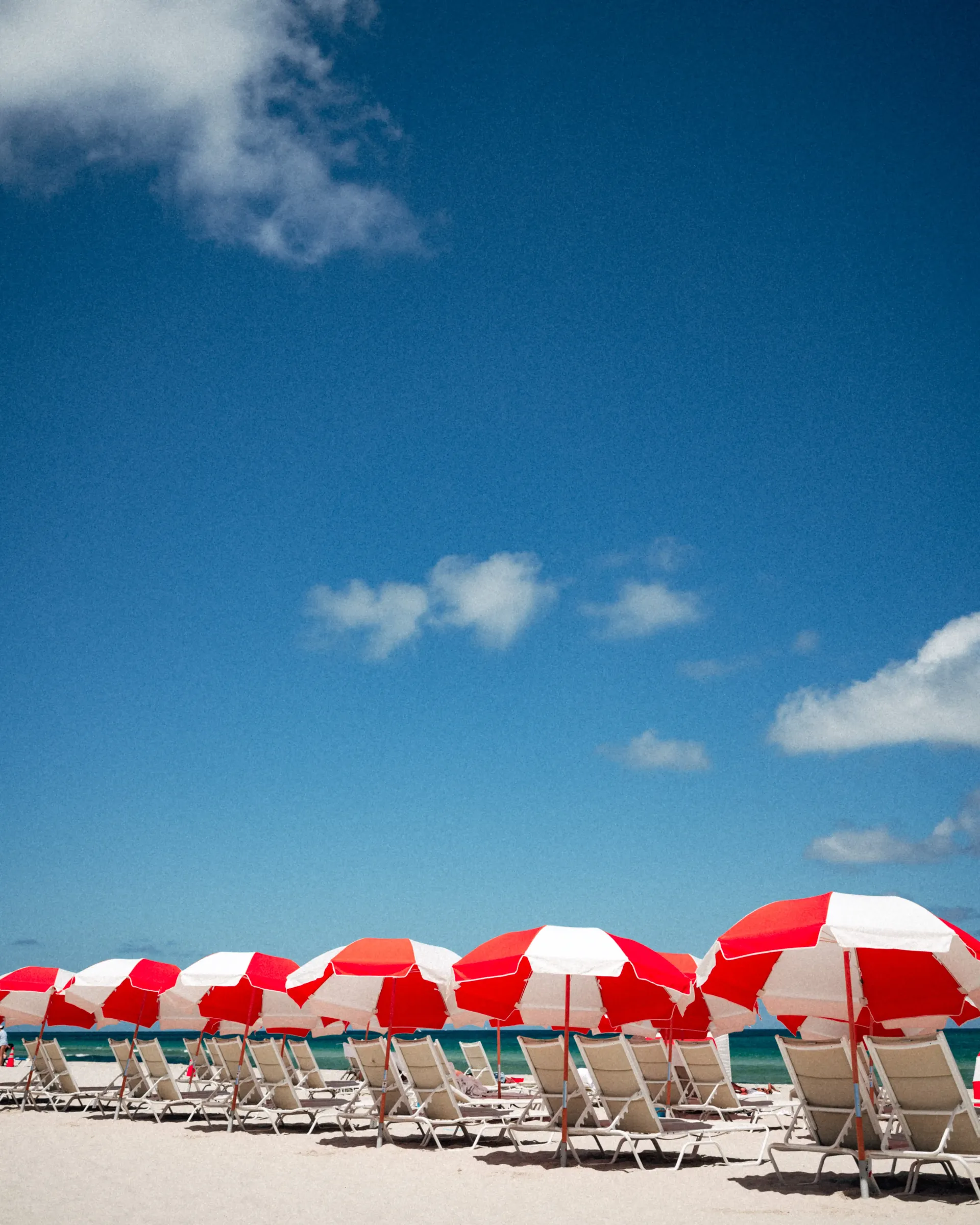 Miami Beach umbrellas and sandy shoreline under sunny sky