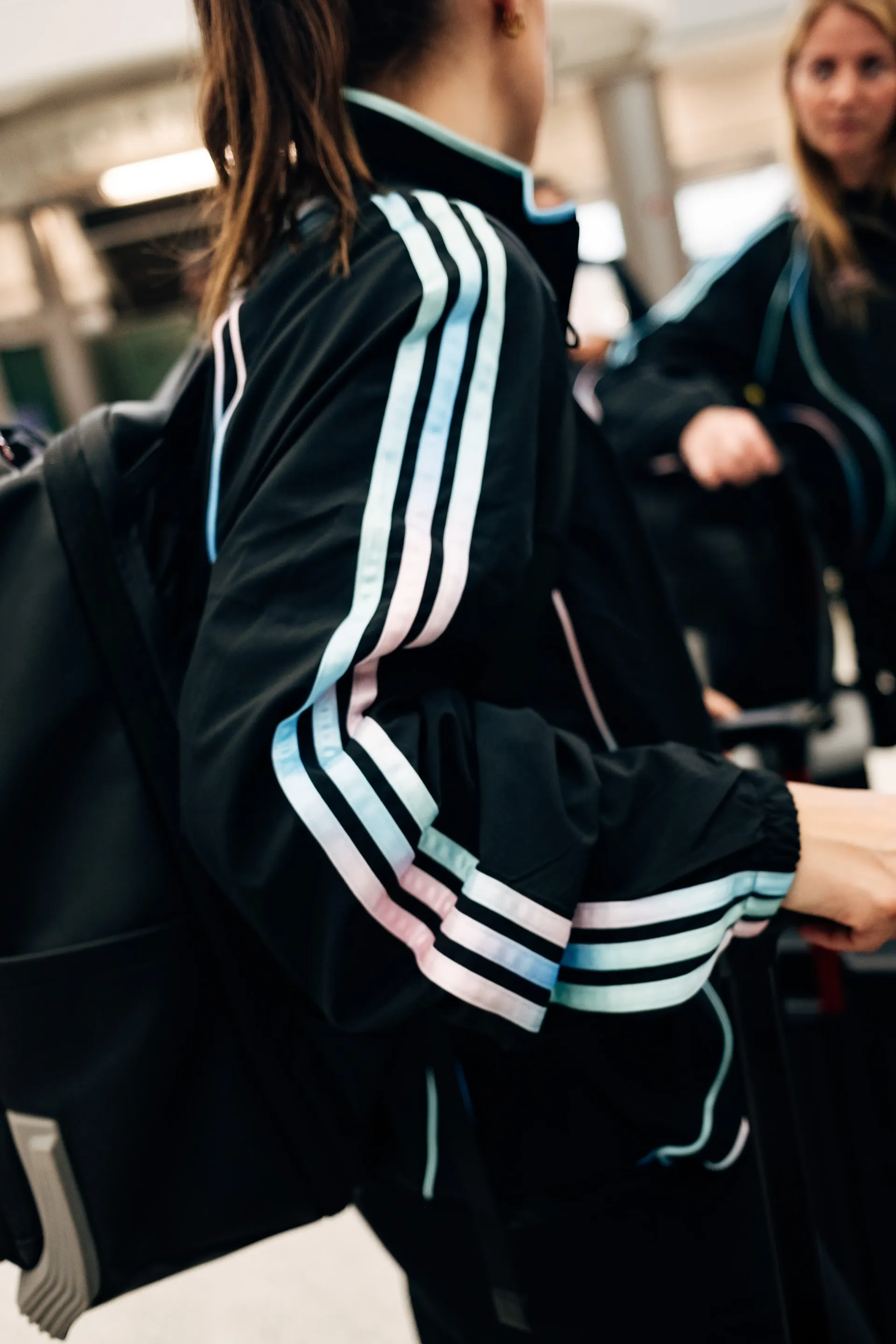 Close-up of  Audi Revolut F1®Team crew member walking through terminal corridor in the new Miami collection tracksuit.