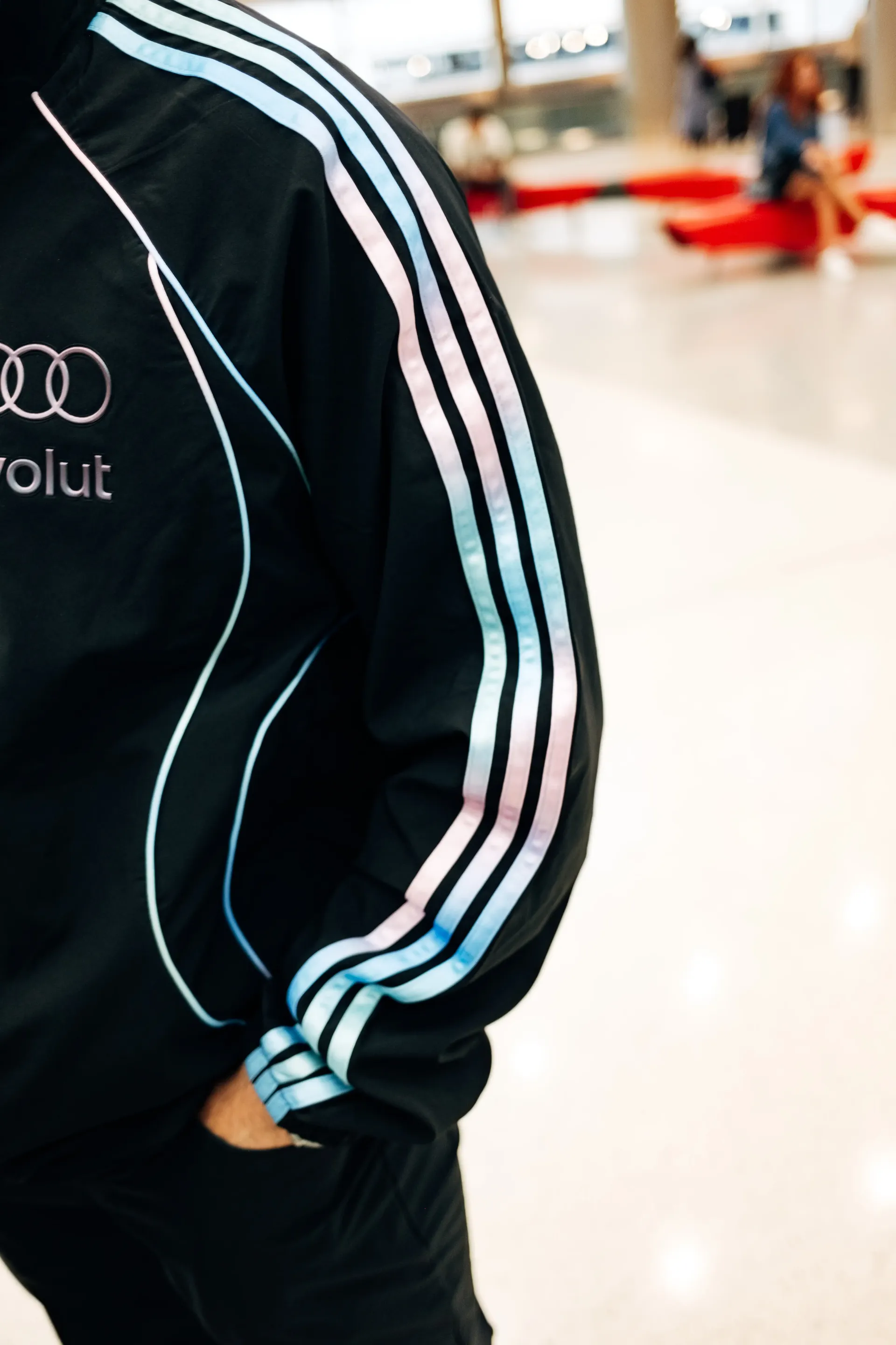 Close-up of  Audi Revolut F1®Team crew walking through terminal corridor in the new Miami collection tracksuit.