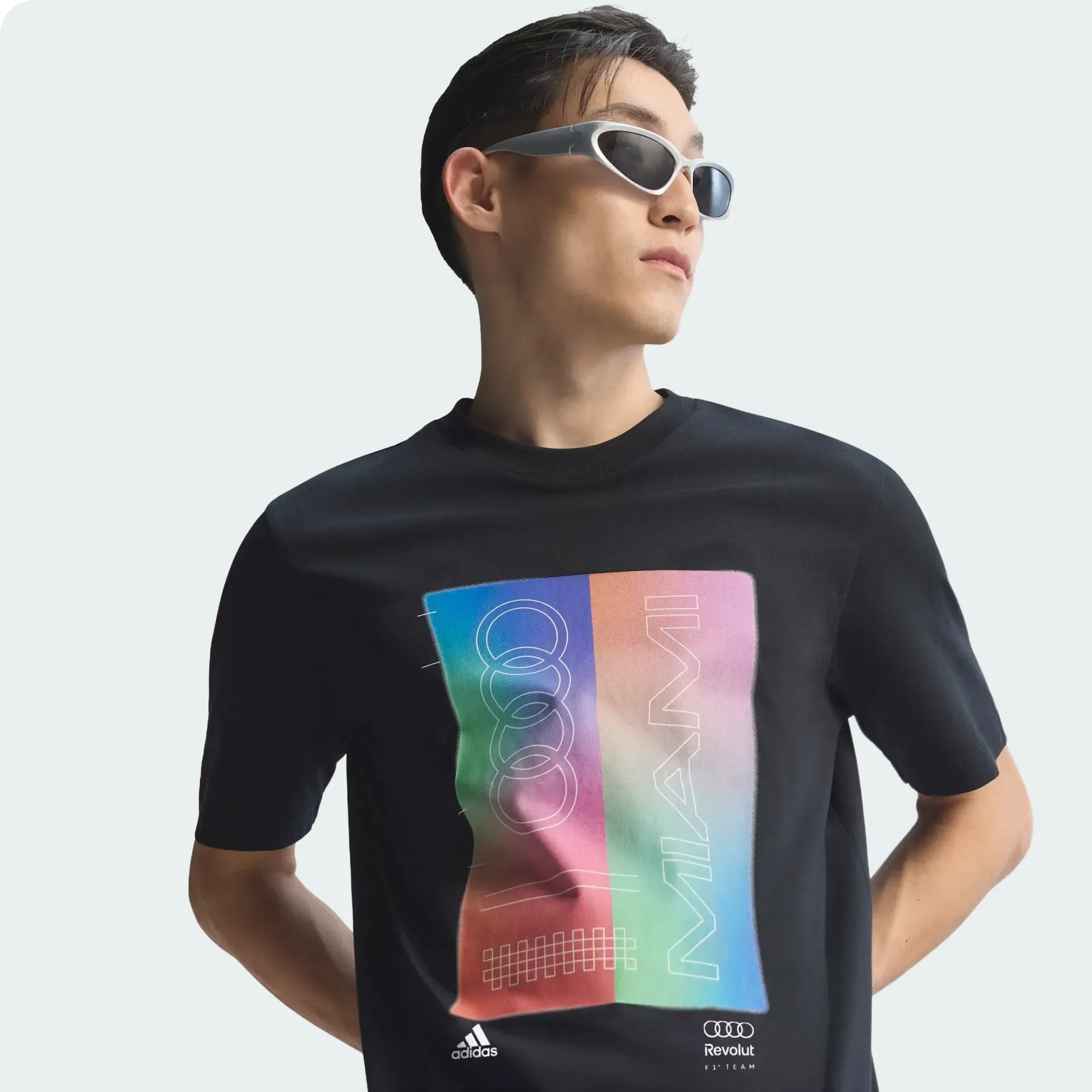 Young male model wearing adidas and Audi Revolut F1® Team Miami collection black graphic tee in the studio