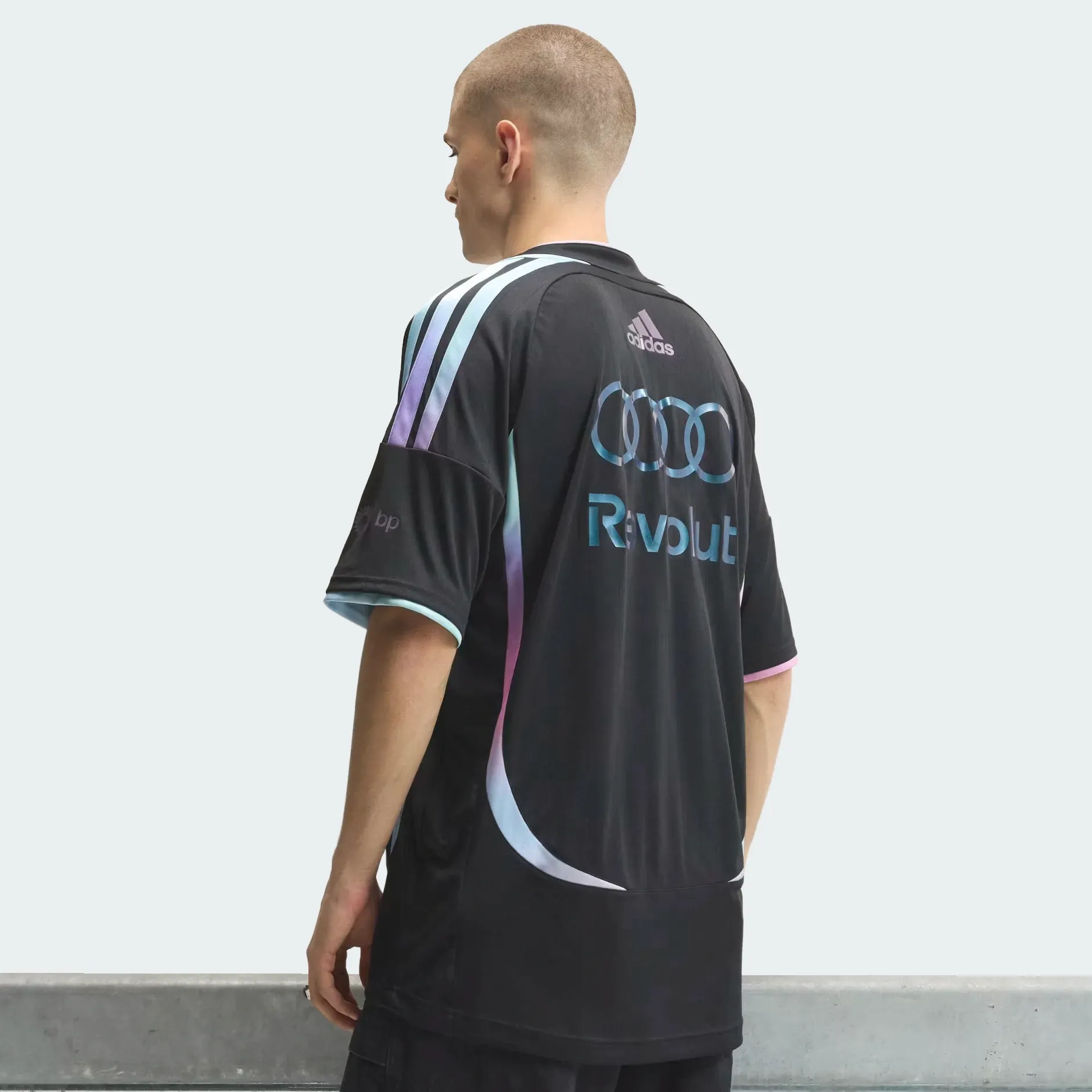 Backshot of a young male model wearing adidas Audi Revolut F1® Team Miami collection driver jersey in the studio
