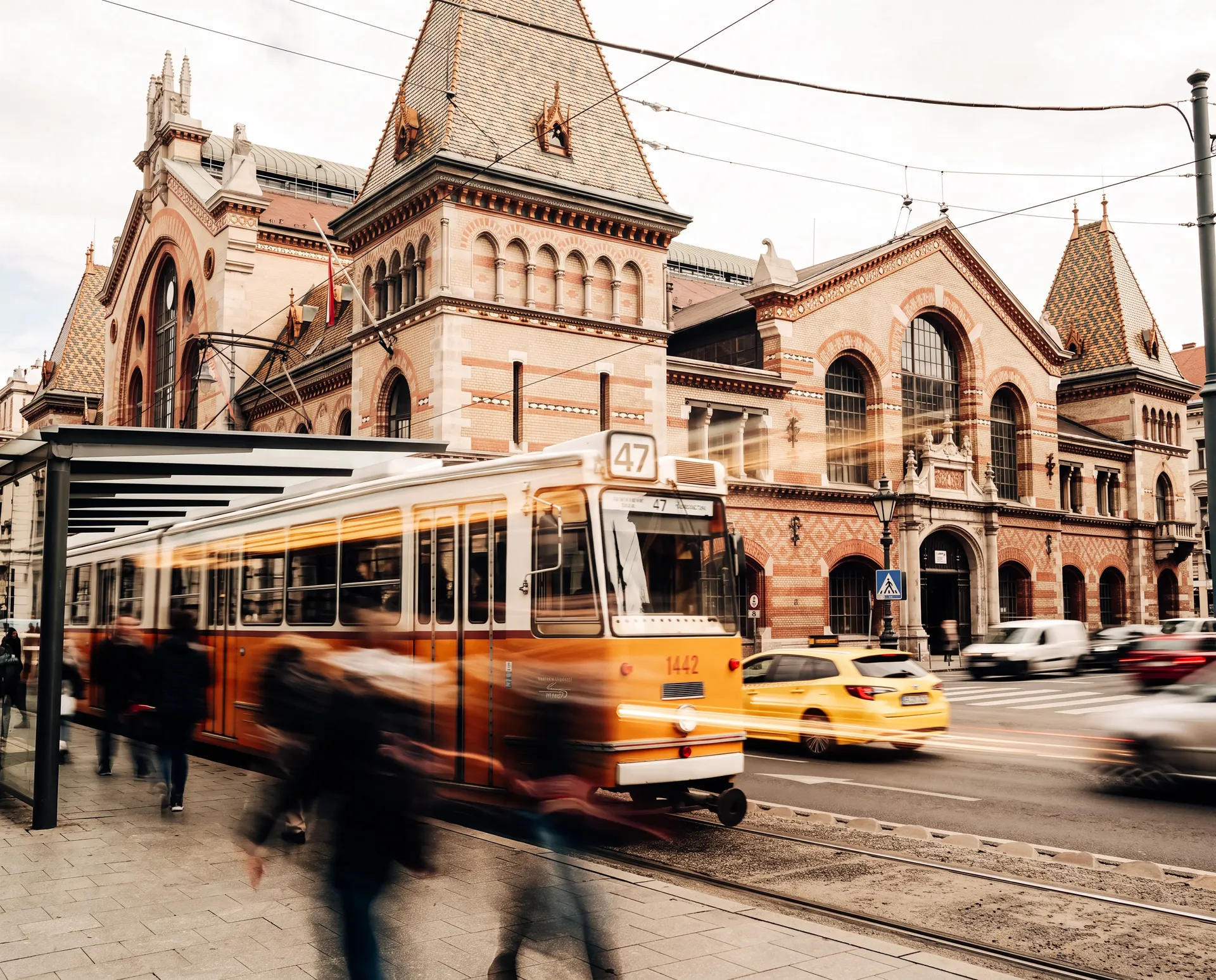 Yellow Budapest tram passing in front of the historic Great Market Hall in Budapest.