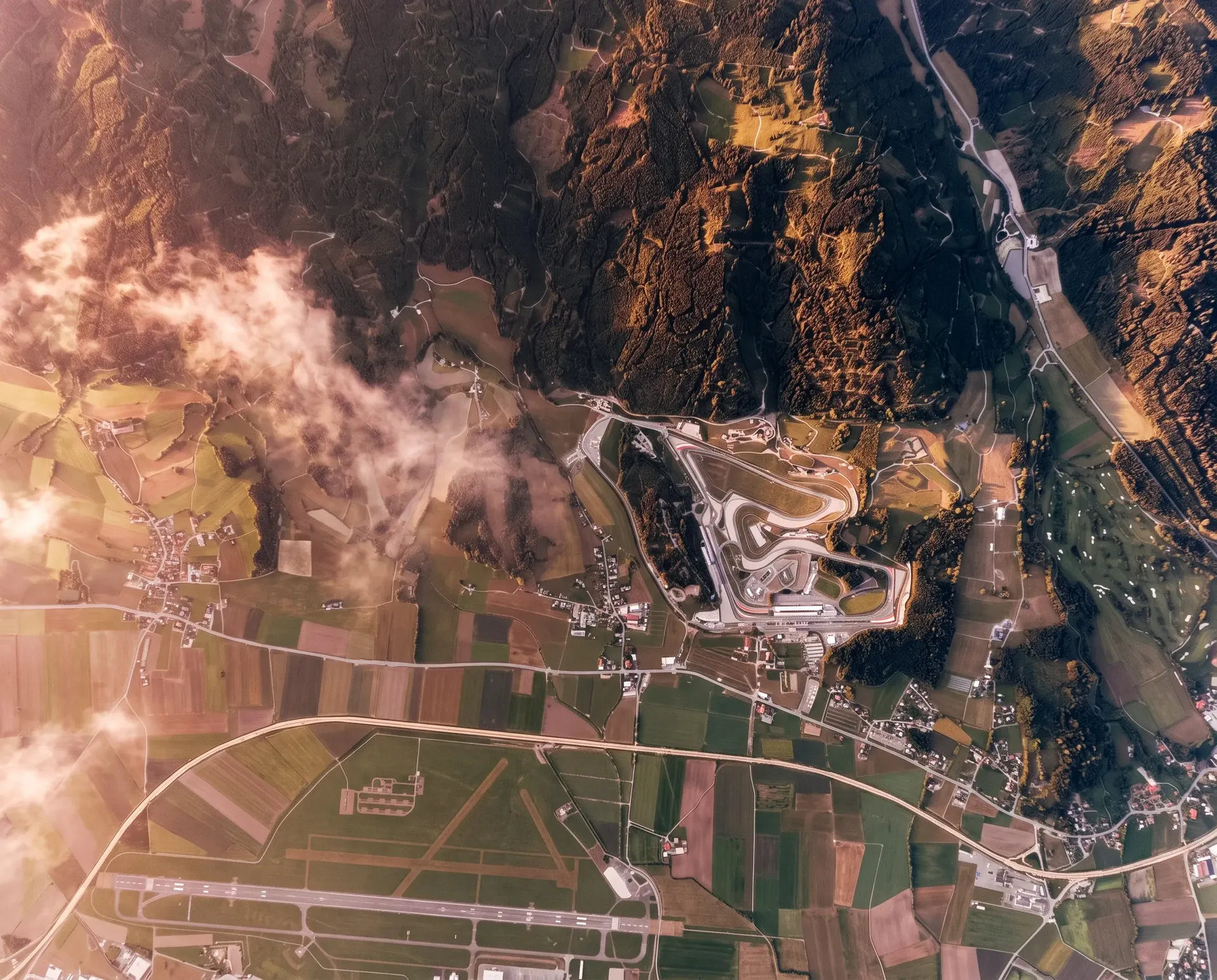 Aerial view of the Red Bull Ring in Spielberg, Austria, winding through the Styrian countryside and mountainous landscape.