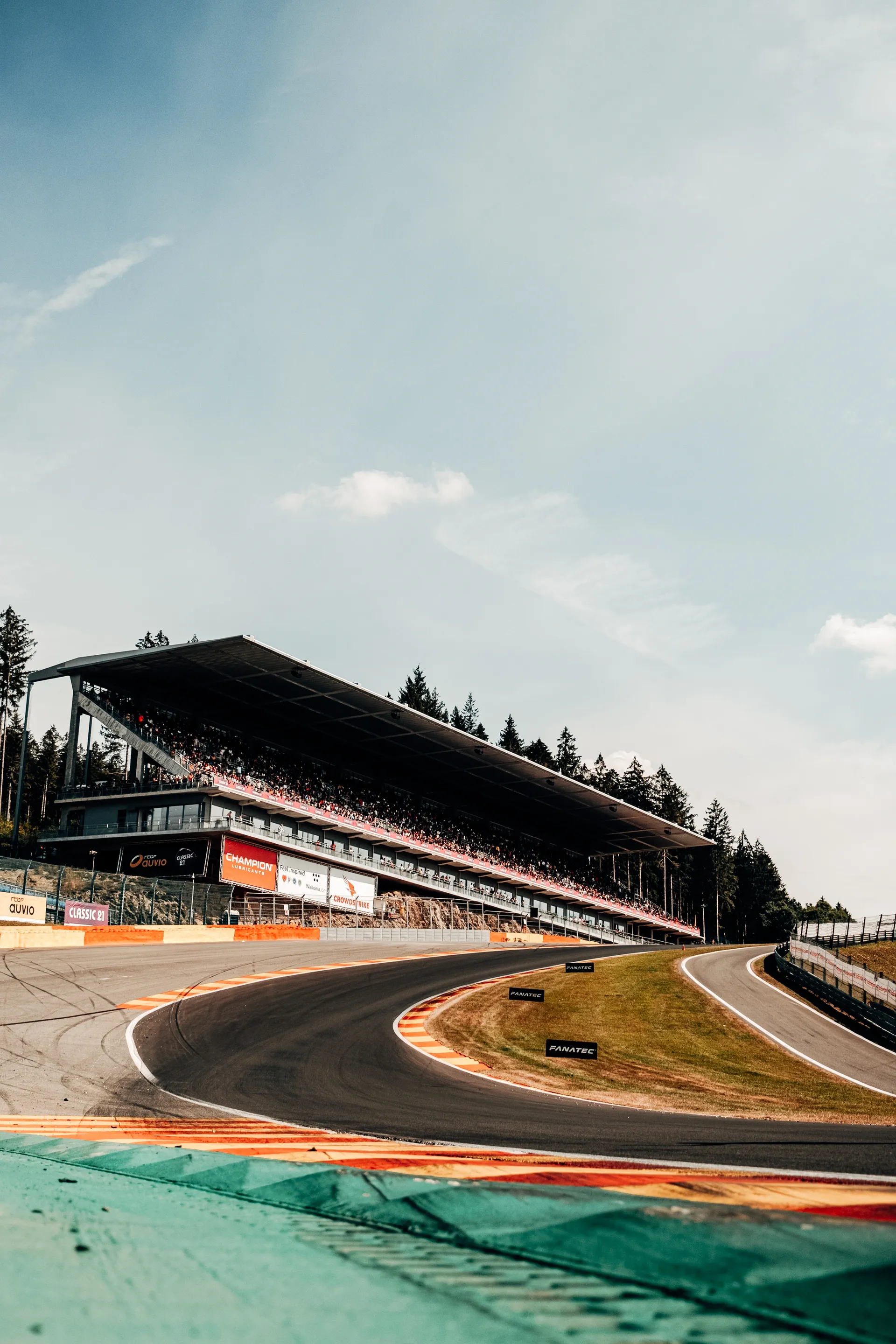 Curving section of the Red Bull Ring with grandstands and mountains visible in the background.