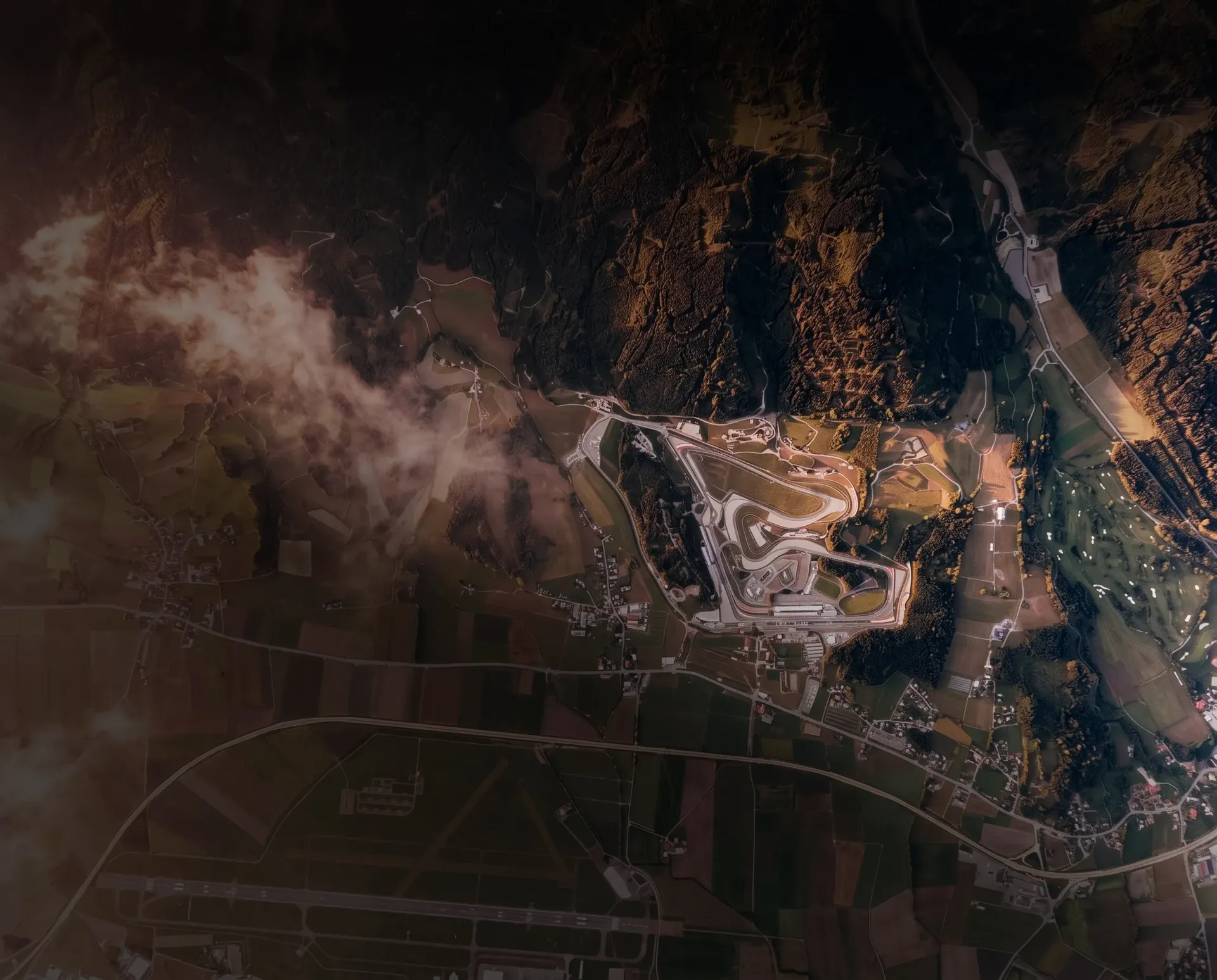 Aerial view of the Red Bull Ring in Spielberg, Austria, winding through the Styrian countryside and mountainous landscape.