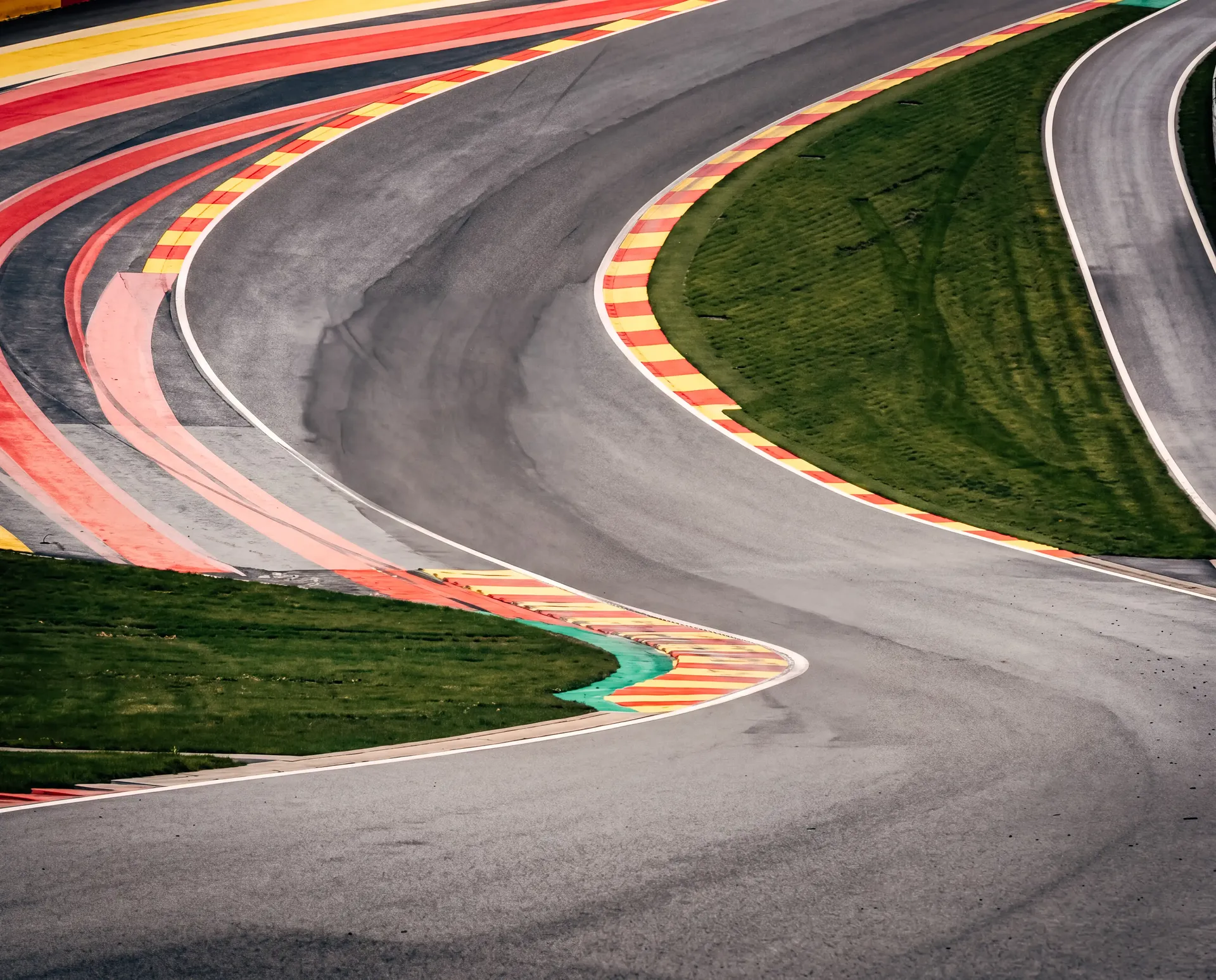Curving section of the Spa-Francorchamps circuit with colorful curbs winding through the landscape.
