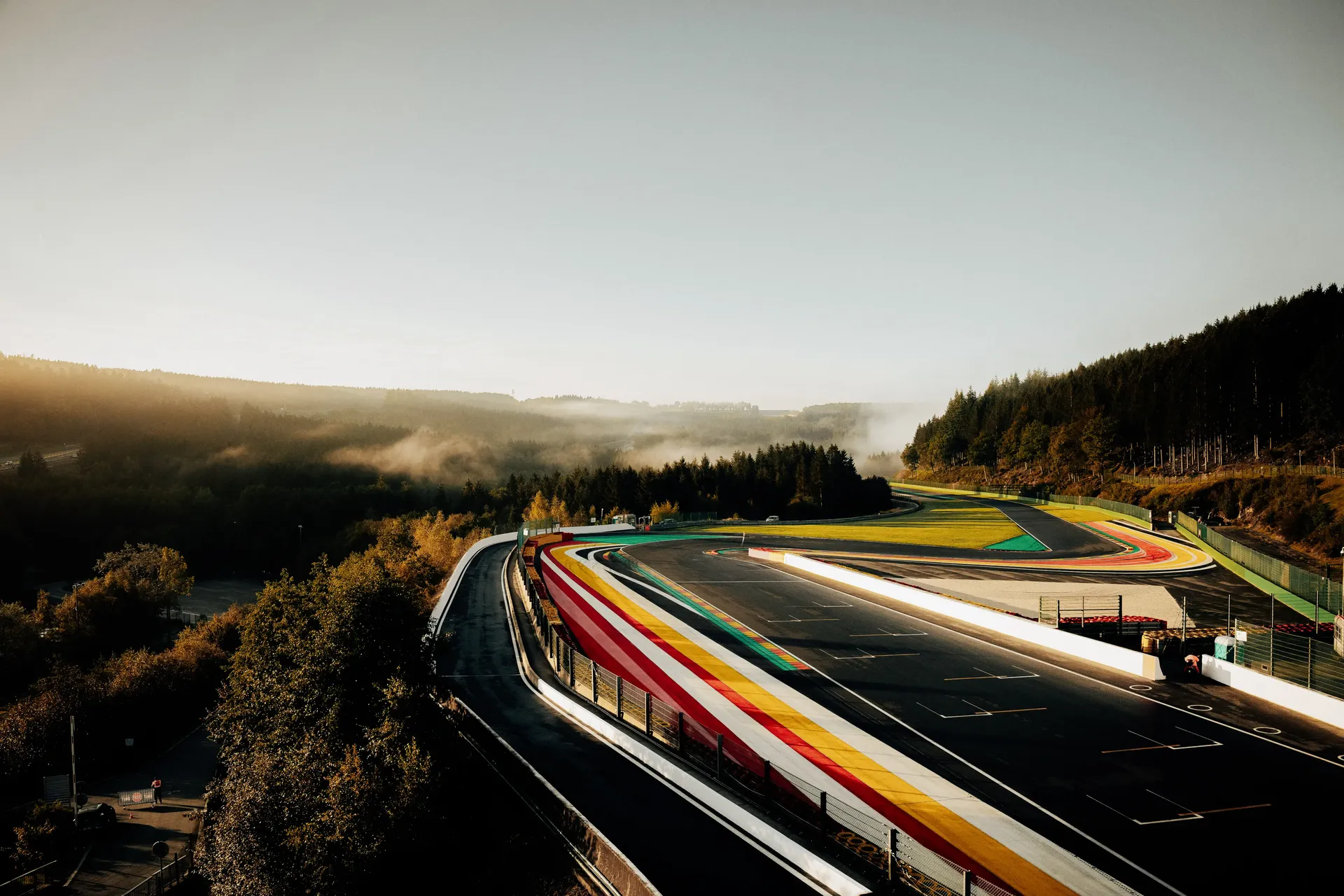 Long-exposure view of Circuit de Spa-Francorchamps with colorful racing light trails curving through the landscape.