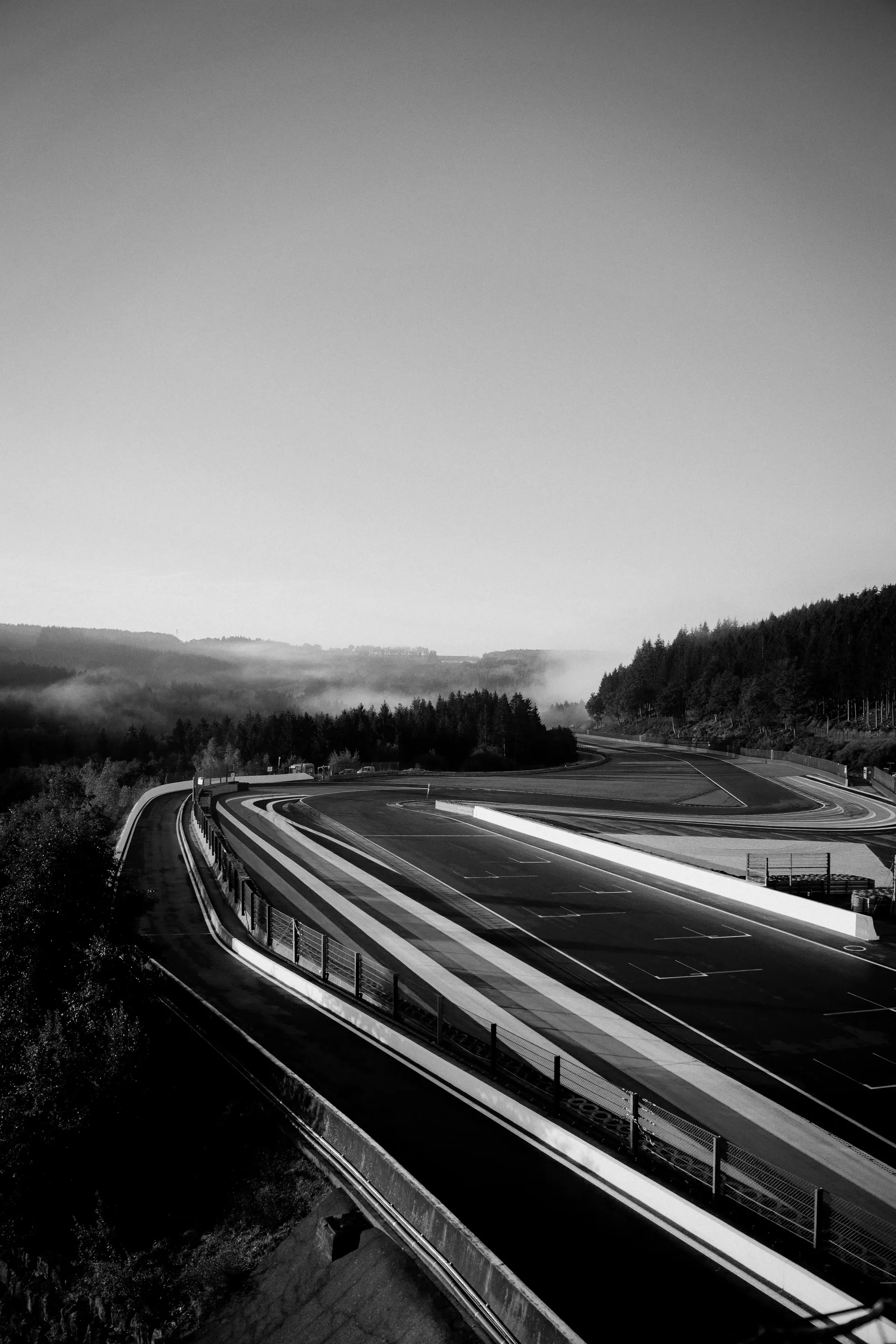 Black-and-white long-exposure image of the Les Combes section with colorful light trails following the racing line.