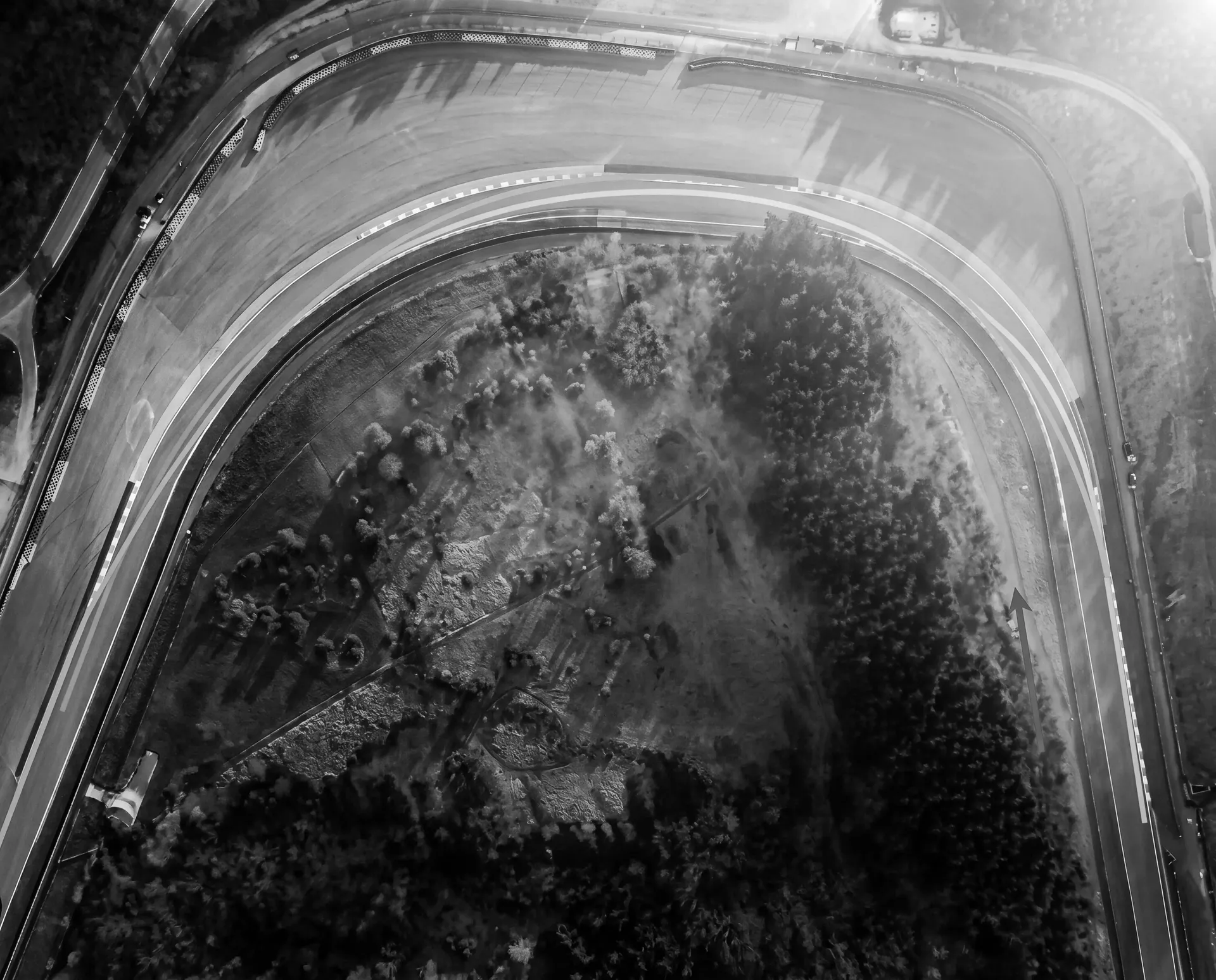 Black-and-white aerial view of the Pouhon double left-hand corner surrounded by trees.
